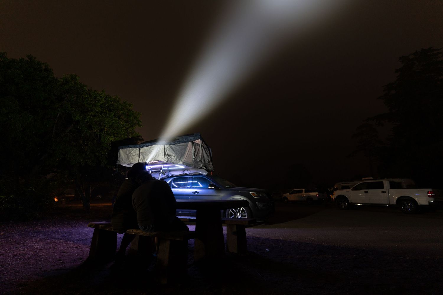 Dark nighttime scene with vehicle headlights illuminating an empty parking area.