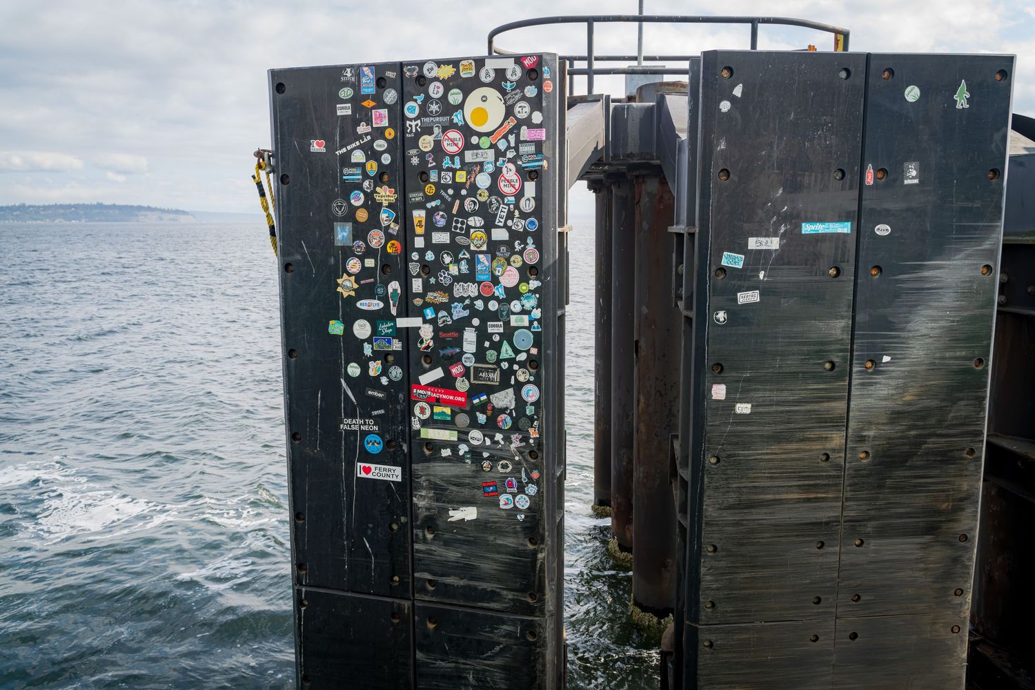 Black metal doors covered in colorful stickers inside a ferry passenger area.