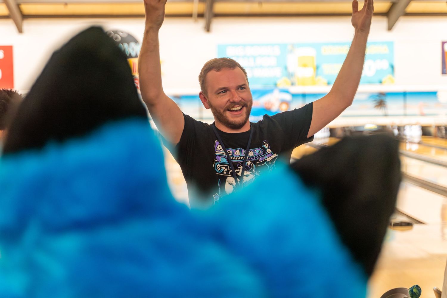 People in fursuits bowling at a lively indoor bowling alley.