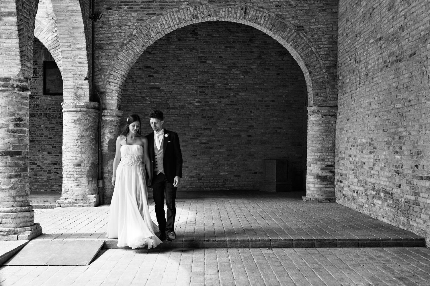 Bride and groom walking through a historic village in Le Marche during their destination wedding