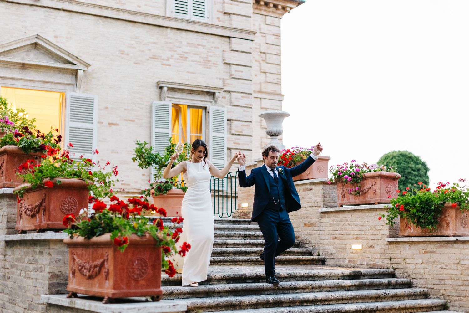 Bride and groom walking down the steps of an elegant villa during a destination wedding in Le Marche, Italy
