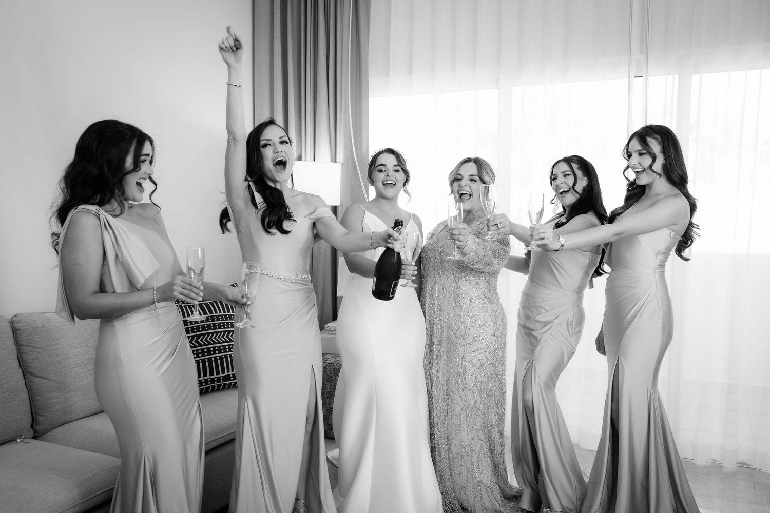 Line of bridesmaids getting ready in matching pink dresses for a wedding celebration.