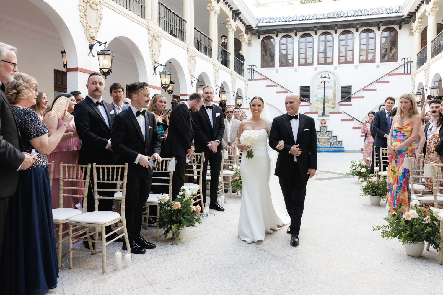 Elegant wedding ceremony and reception sequence showing guests and decor in a grand indoor venue with arched architecture.