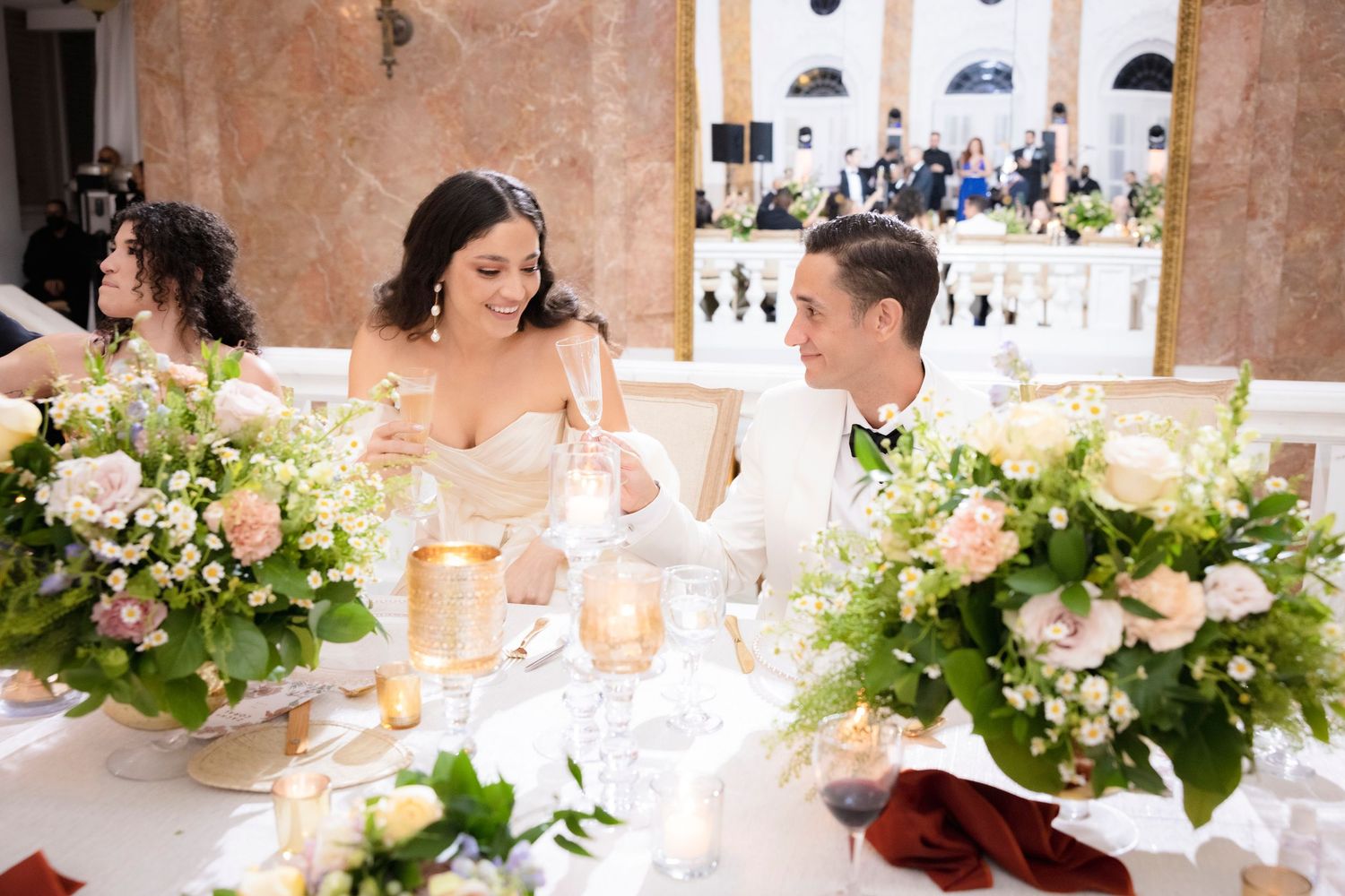 Elegant floral arrangements with green foliage decorate a wedding reception venue.