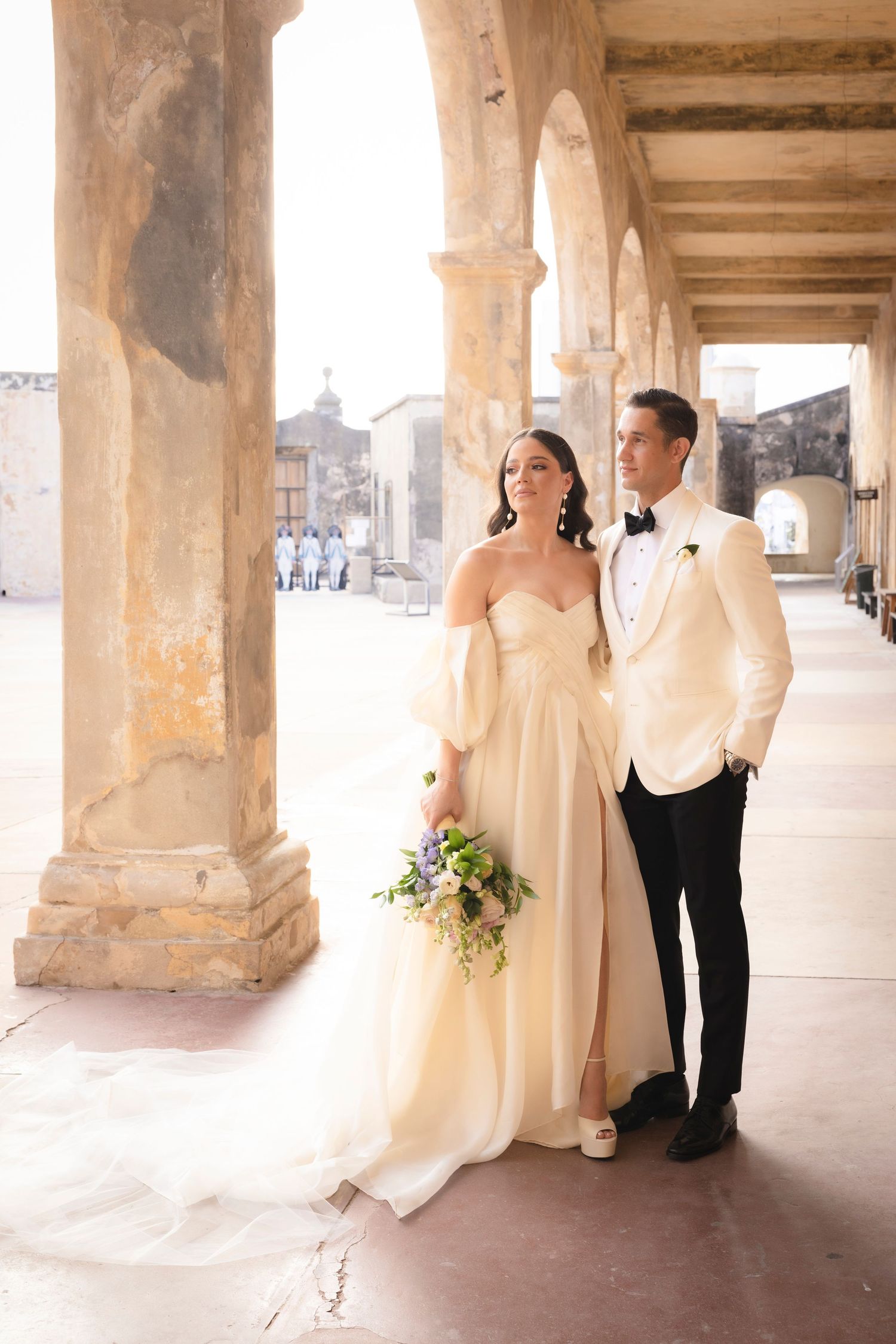 A romantic wedding photoshoot under stone archways with dramatic lighting and elegant poses.