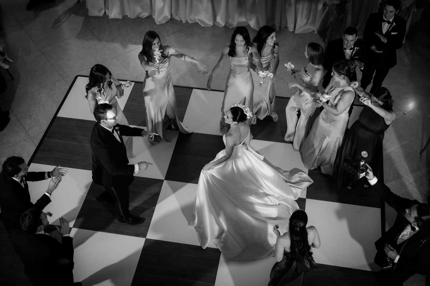 A group of dancers in white dresses perform a synchronized dance routine on stage during a performance.