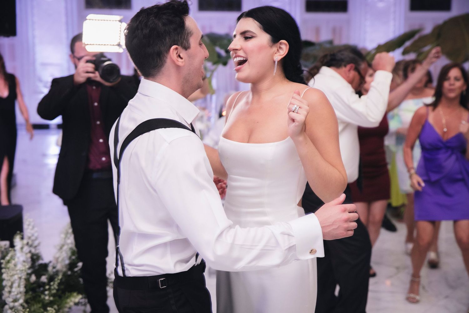 Couples dancing and celebrating at an elegant wedding reception with white decor.