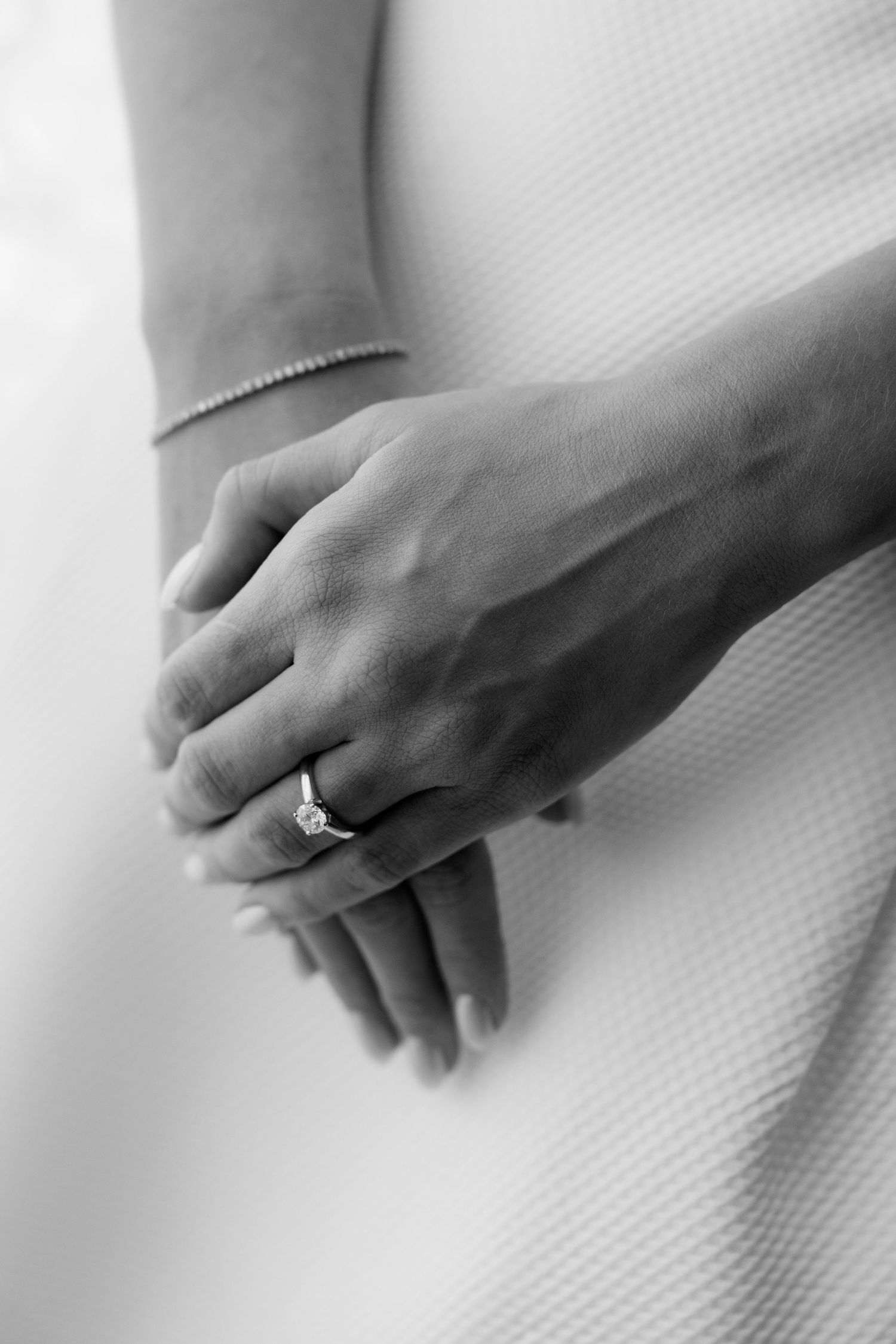 Black and white progression shot of two clasped hands slowly releasing their grip against a white textured background.