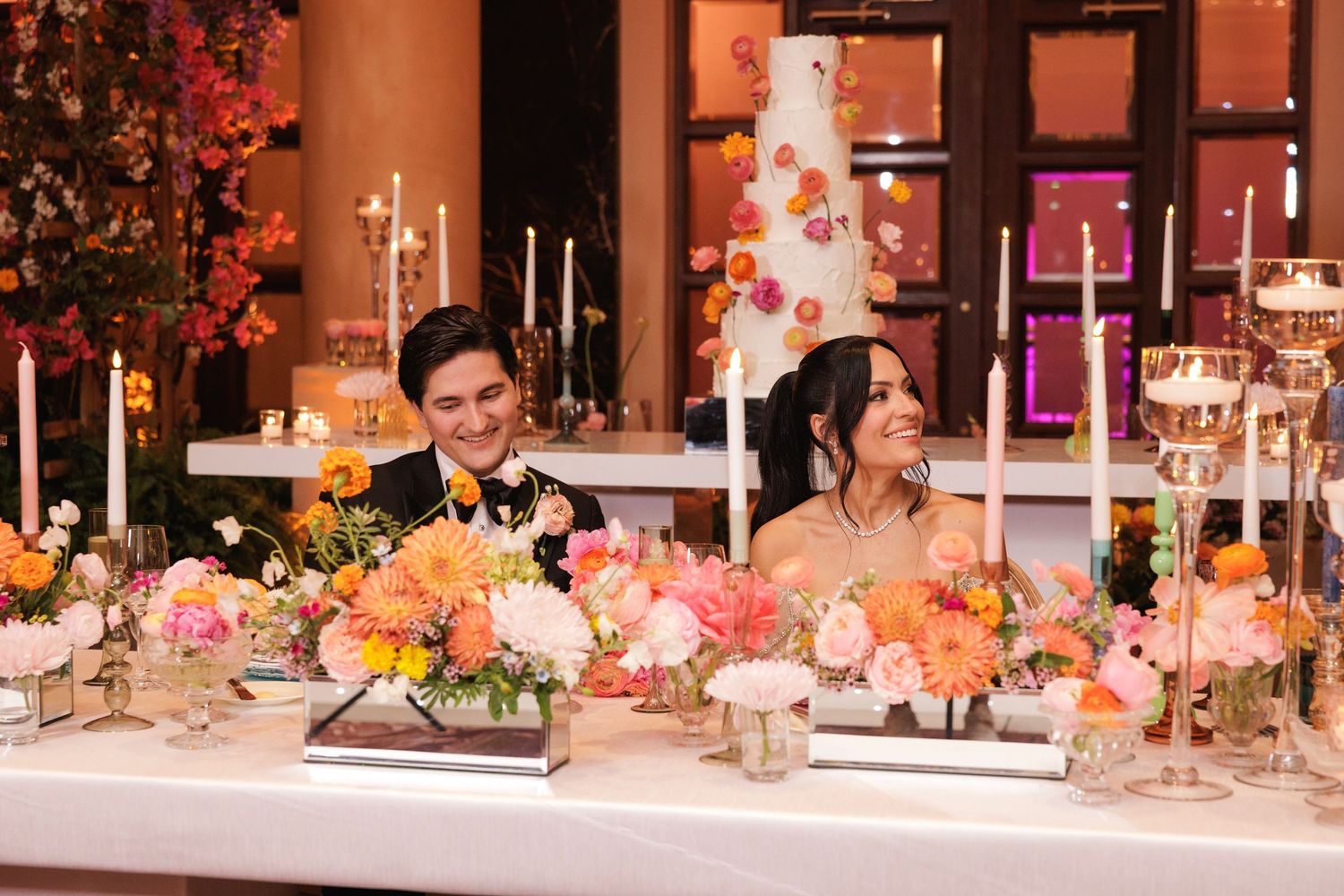 Wedding reception venue featuring pink floral decorations and table settings in a grand ballroom setting.