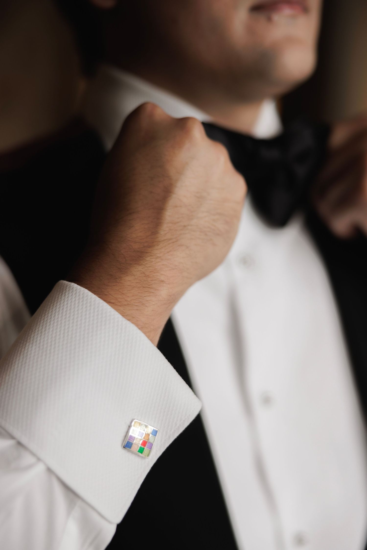 Close-up of formal white dress shirt cuff with colorful cufflinks.