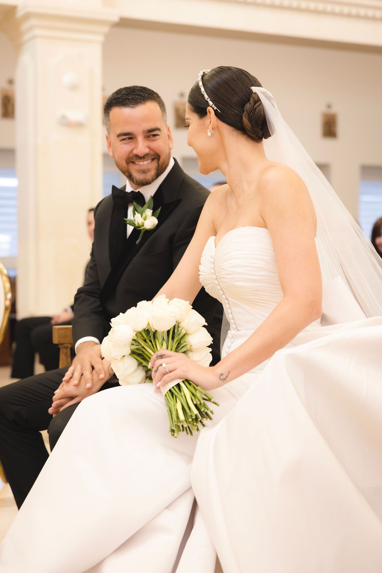 A joyful wedding ceremony moment shared between a couple in white attire at an elegant indoor venue.