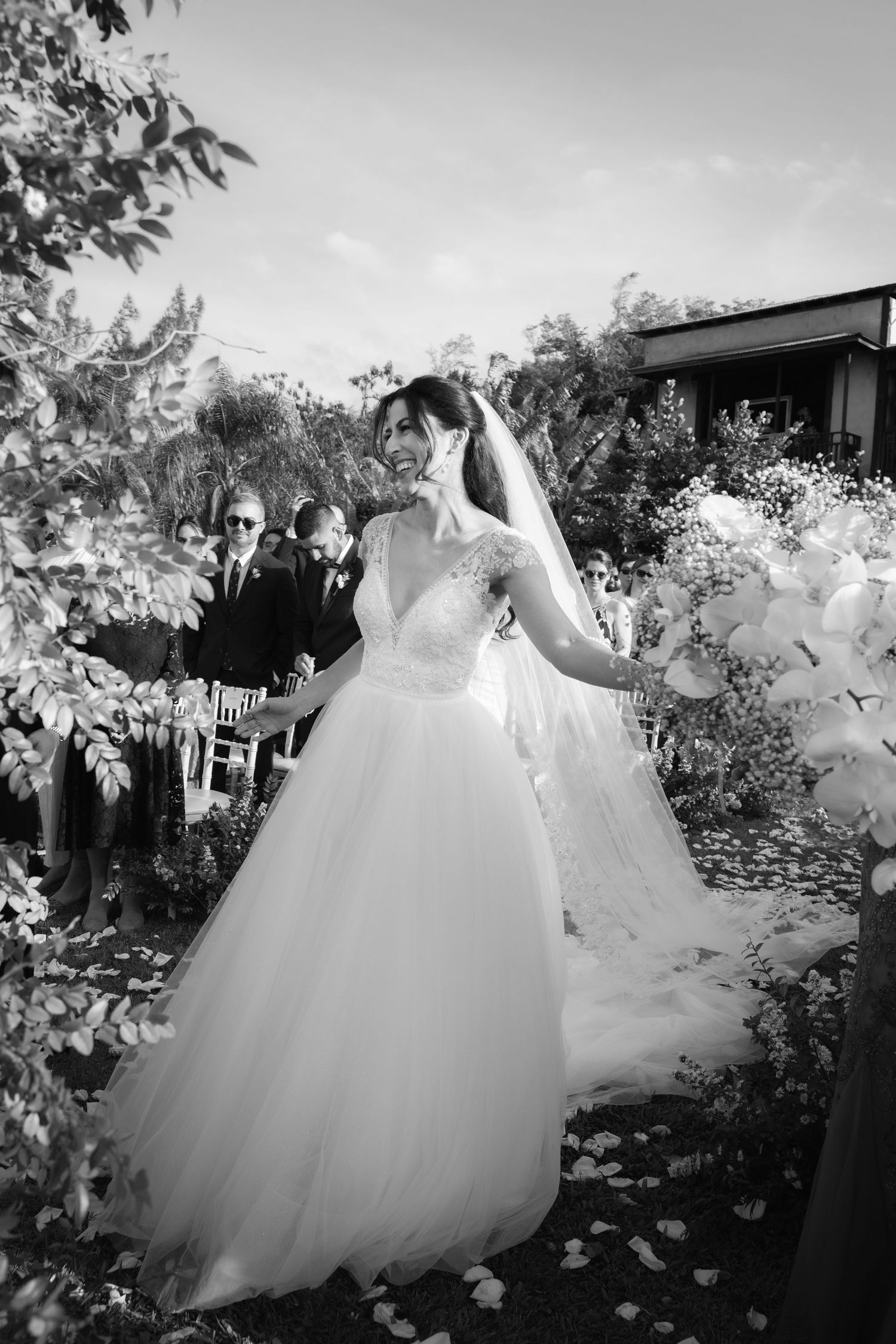 Black and white photograph of wedding dresses flowing in garden setting.
