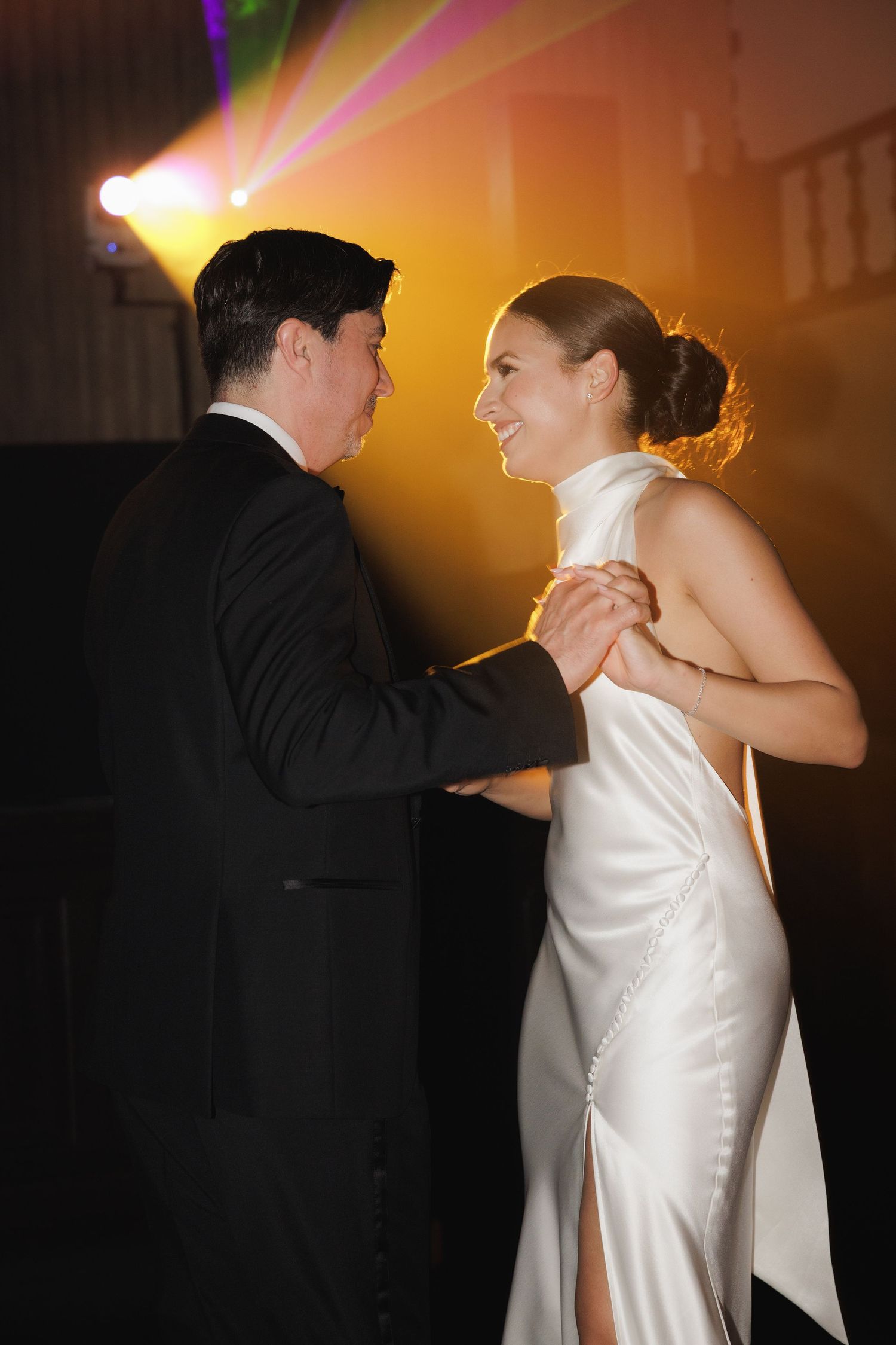 Couple shares a romantic dance moment in warm lighting during their wedding reception.