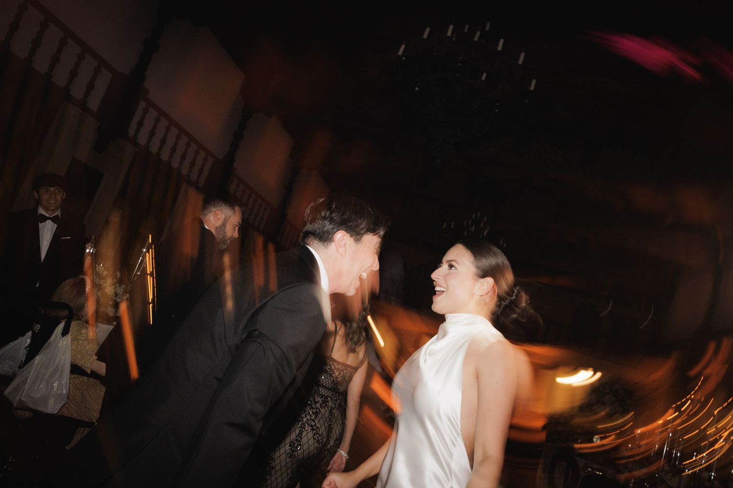 Wedding celebration captured in low light with dancing silhouettes and festive atmosphere.