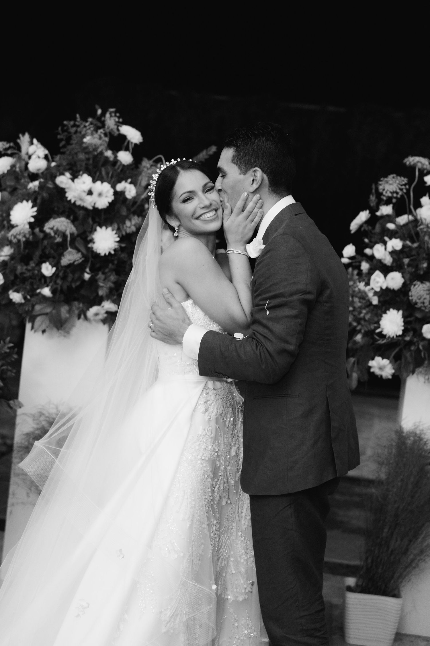 Black and white wedding photos capturing intimate moments against a floral backdrop.