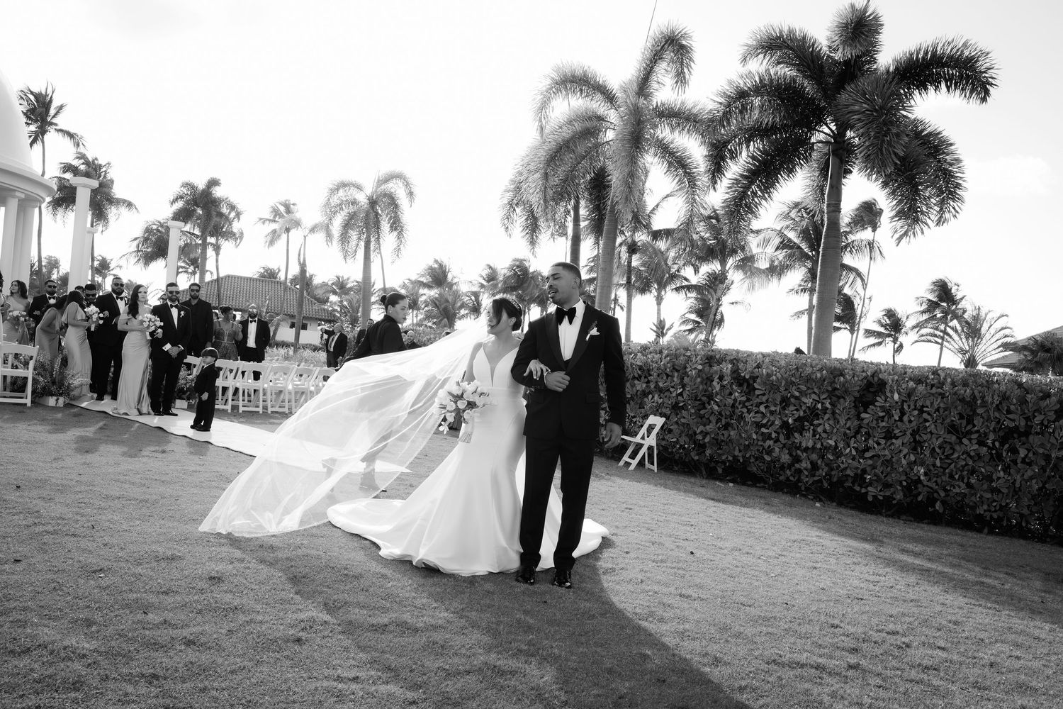 Black and white wedding photos display romantic scenes of a couple celebrating their special day in a tropical setting.