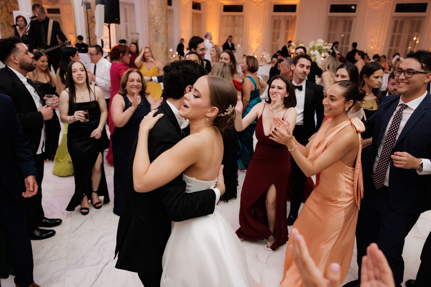 Wedding guests dance and celebrate together on an illuminated dance floor at an elegant reception venue.