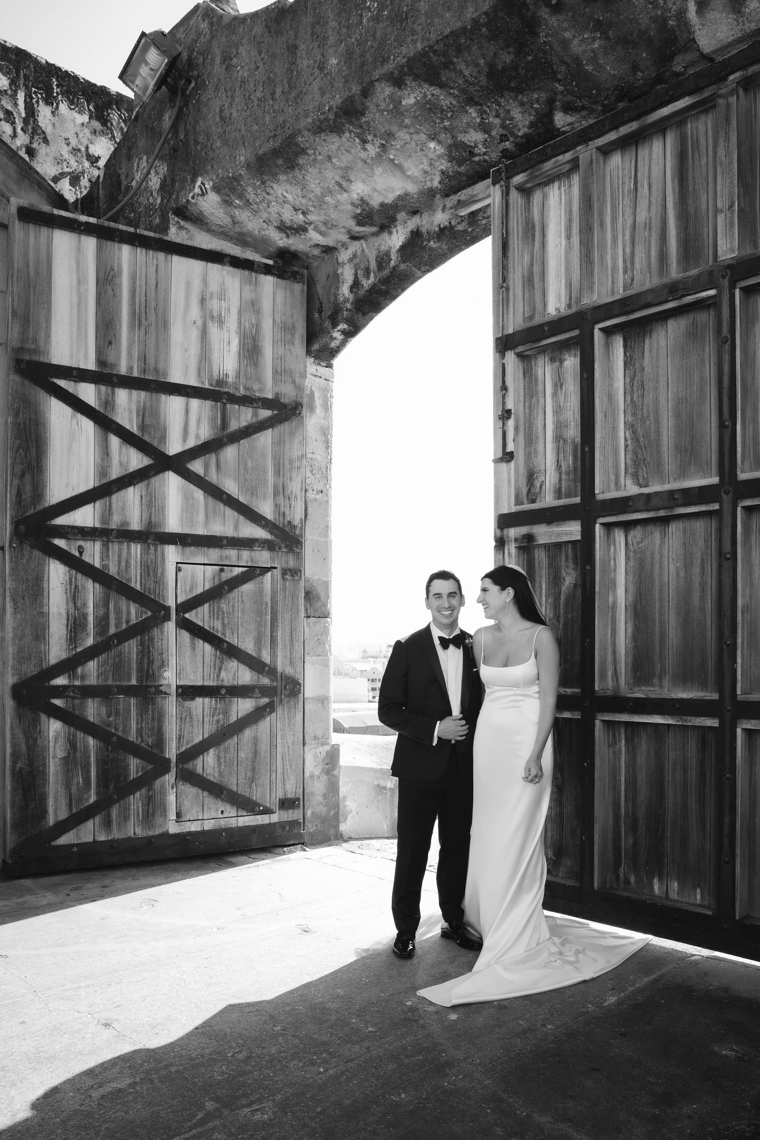 Dramatic black and white architectural wedding photos taken against rustic wooden walls and doorways.