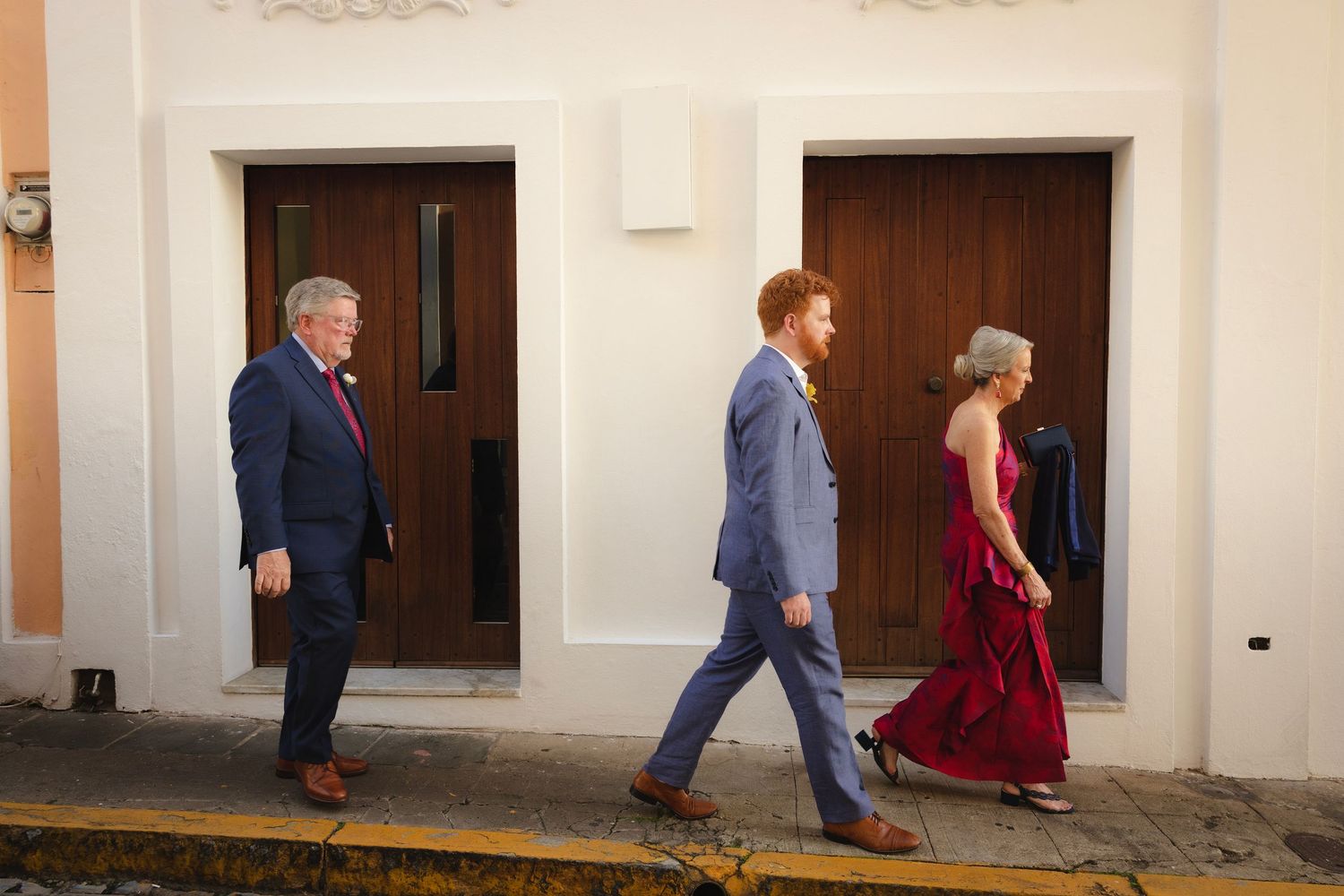 Wedding party walking down a corridor with striking shadows and sunlight streaming through windows.