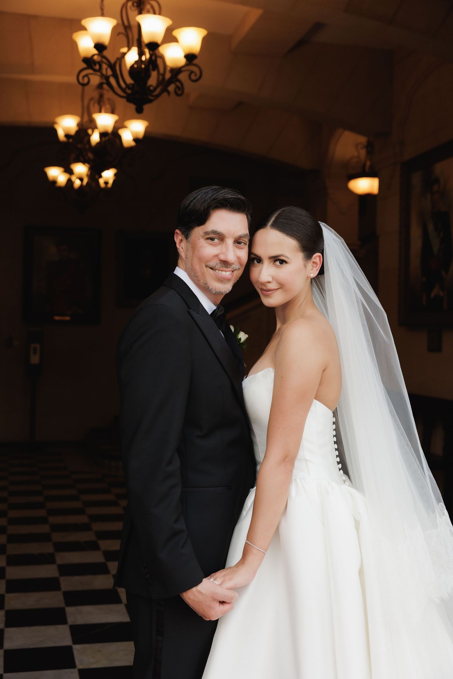 Romantic wedding portraits captured in an elegant ballroom with black and white checkered floors.