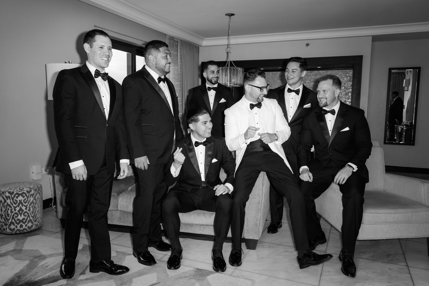 A group of groomsmen in black tuxedos perform a synchronized dance routine at a wedding reception.