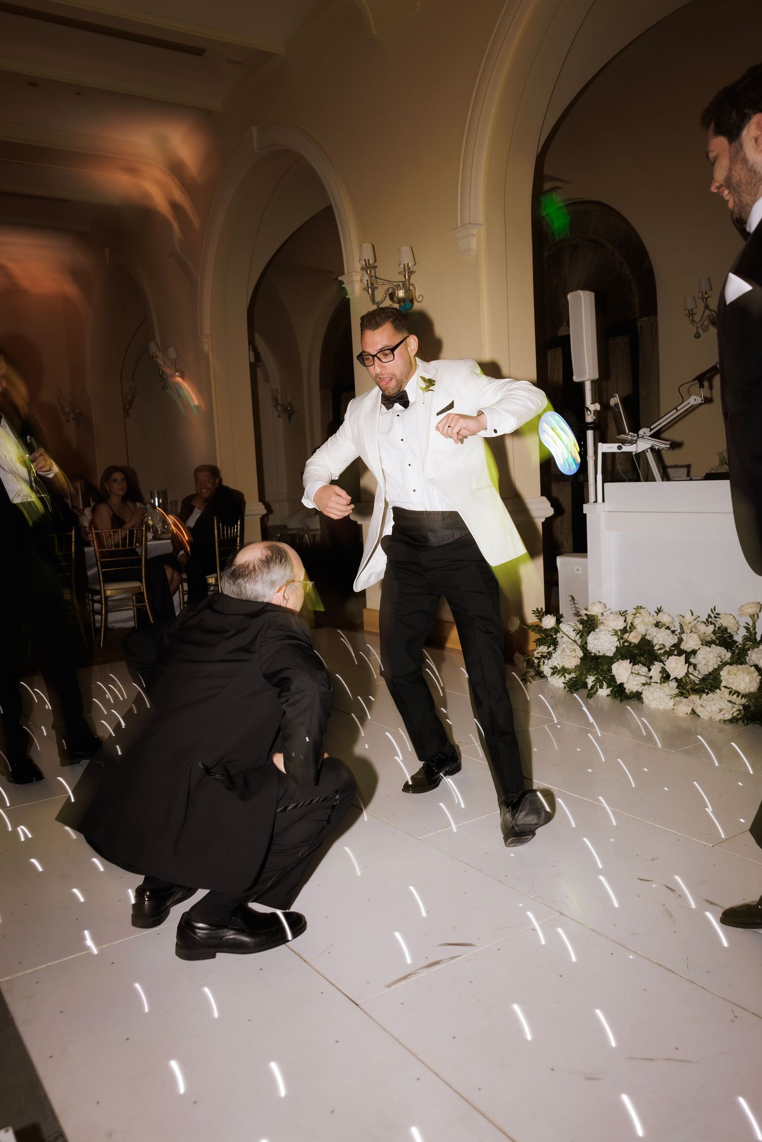 Sequence of photos showing a person performing a backflip on a dance floor at a formal event.