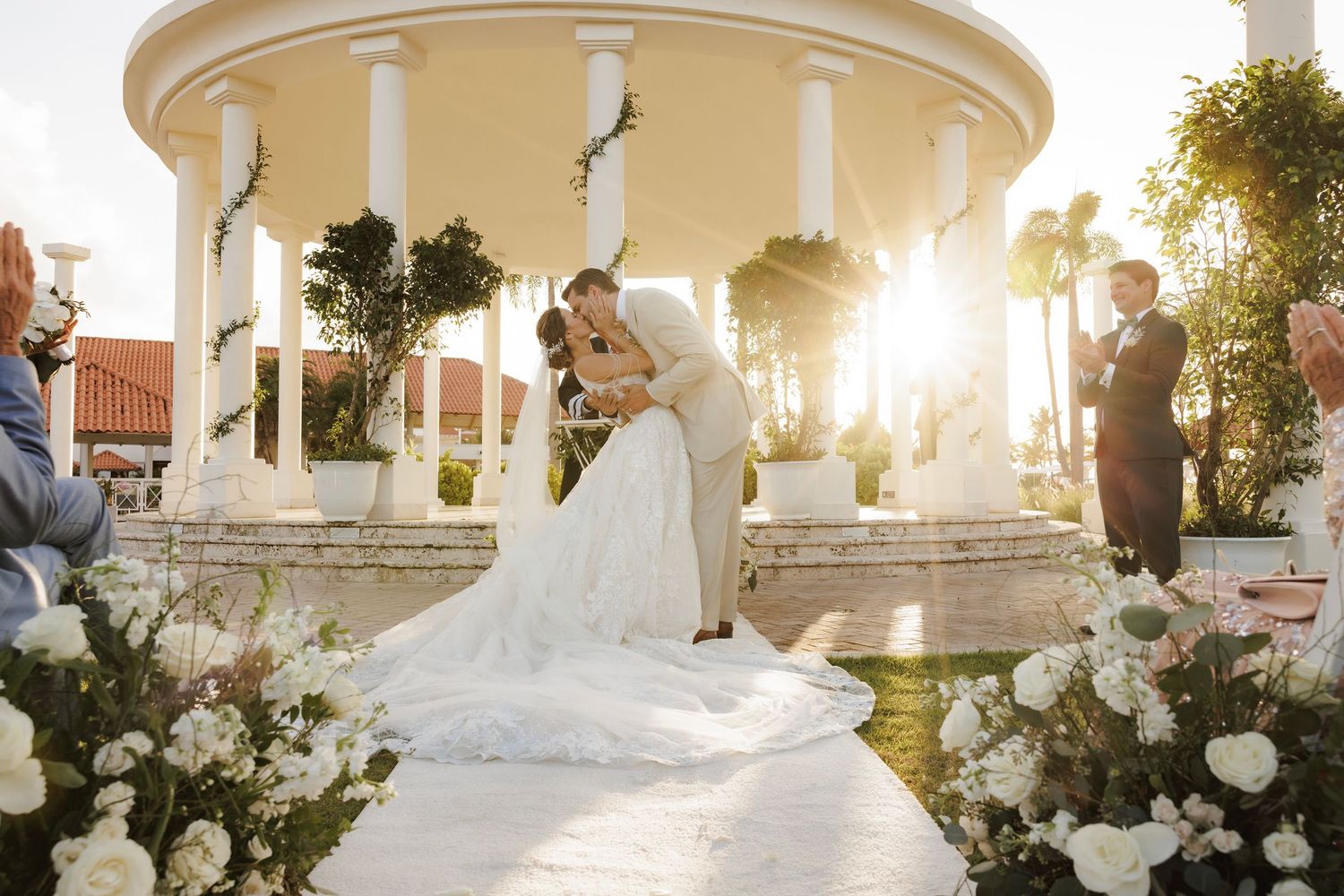 A joyful romantic moment with dancing in a beautiful wedding venue surrounded by white floral arrangements and columns.