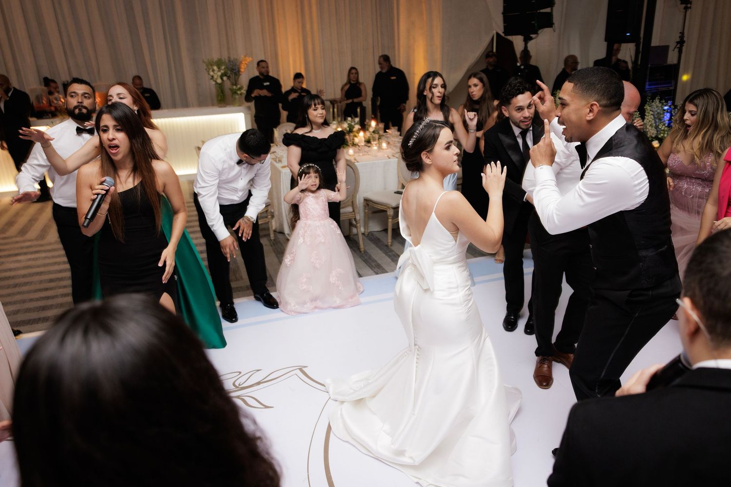 A wedding party dances and celebrates together on the dance floor during an evening reception.