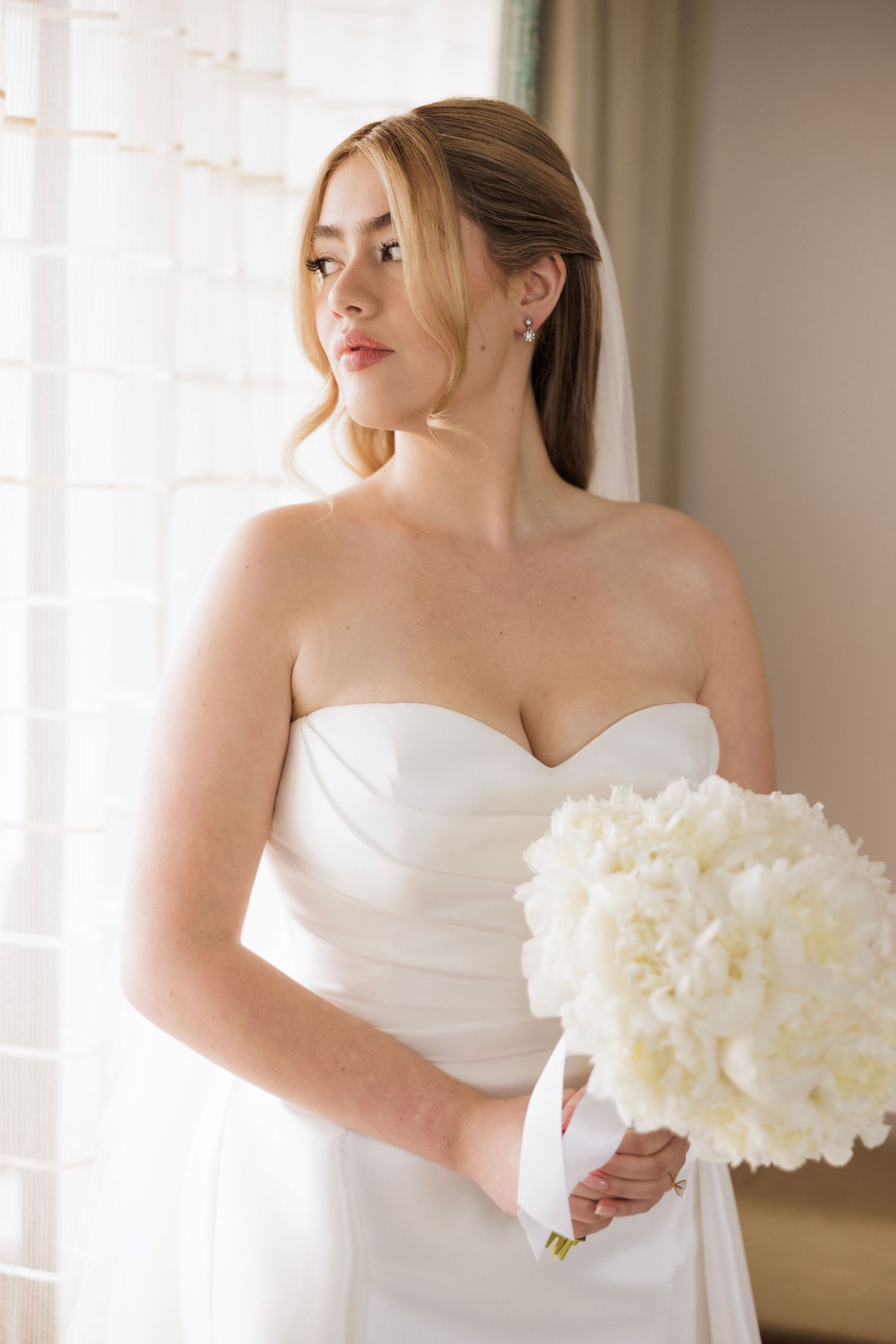 Elegant white wedding dress with sweetheart neckline and white peony bouquet.