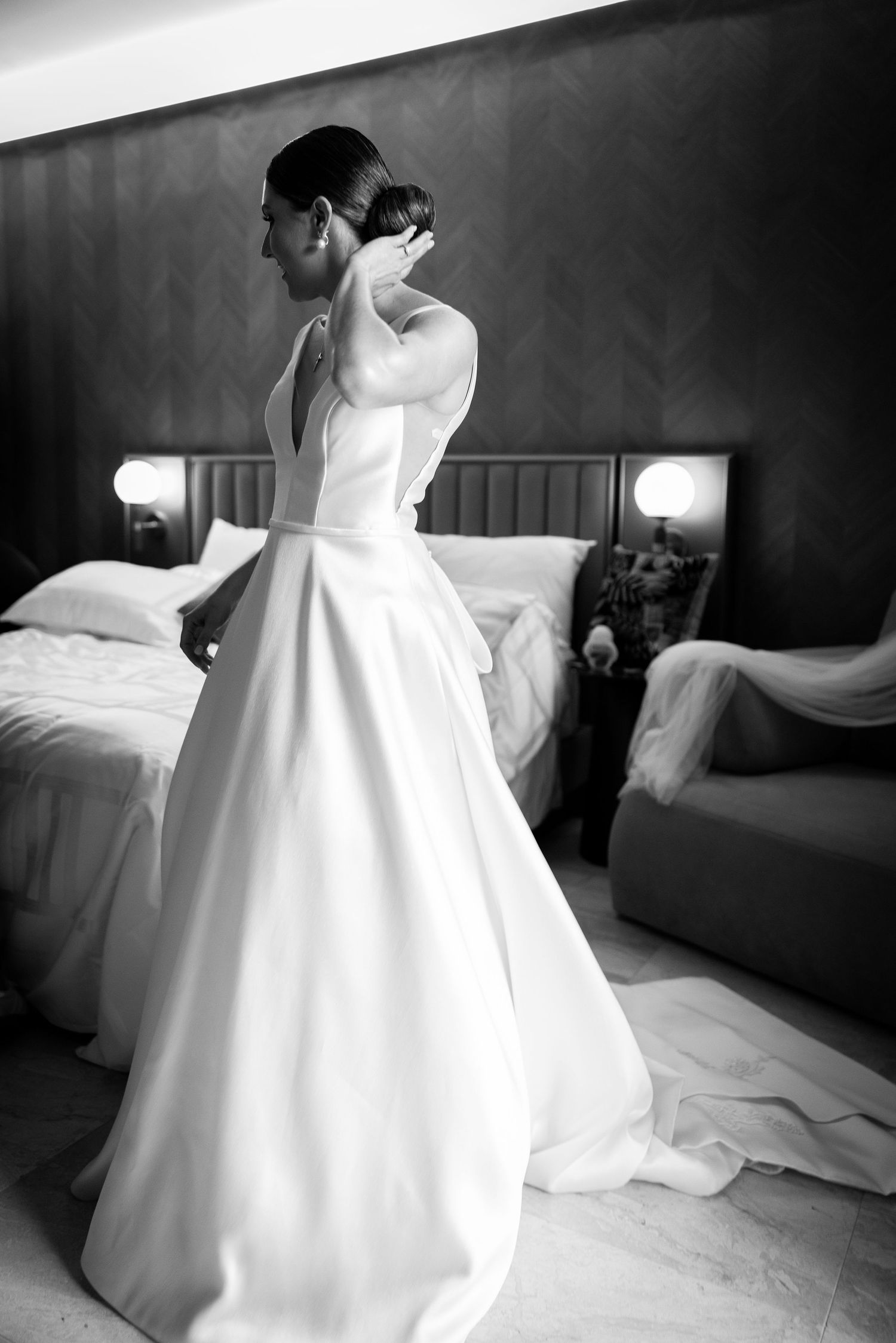 White ballgown wedding dress flowing elegantly across a hotel room bed.