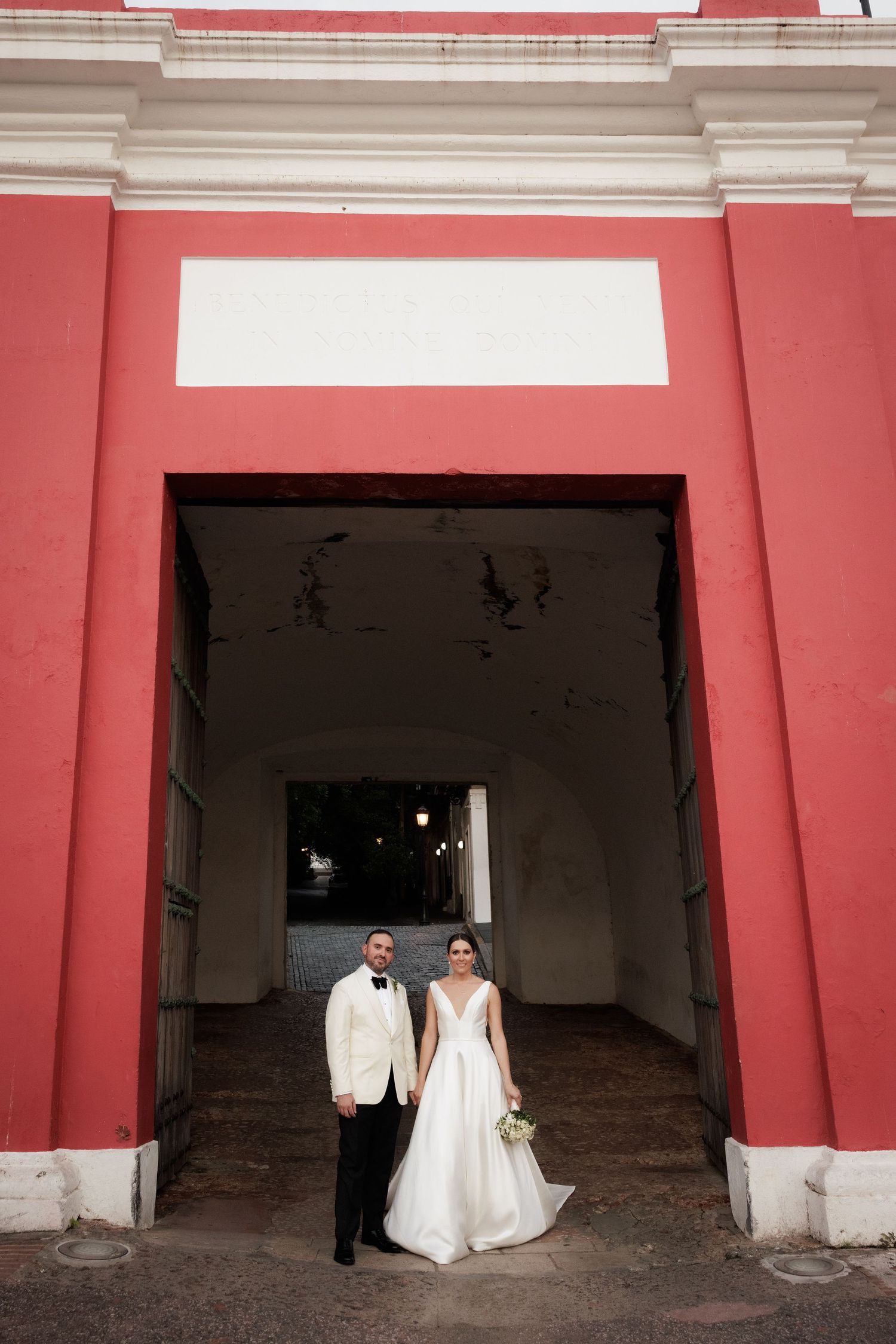 Wedding photo series against a striking red and white colonial archway entrance.