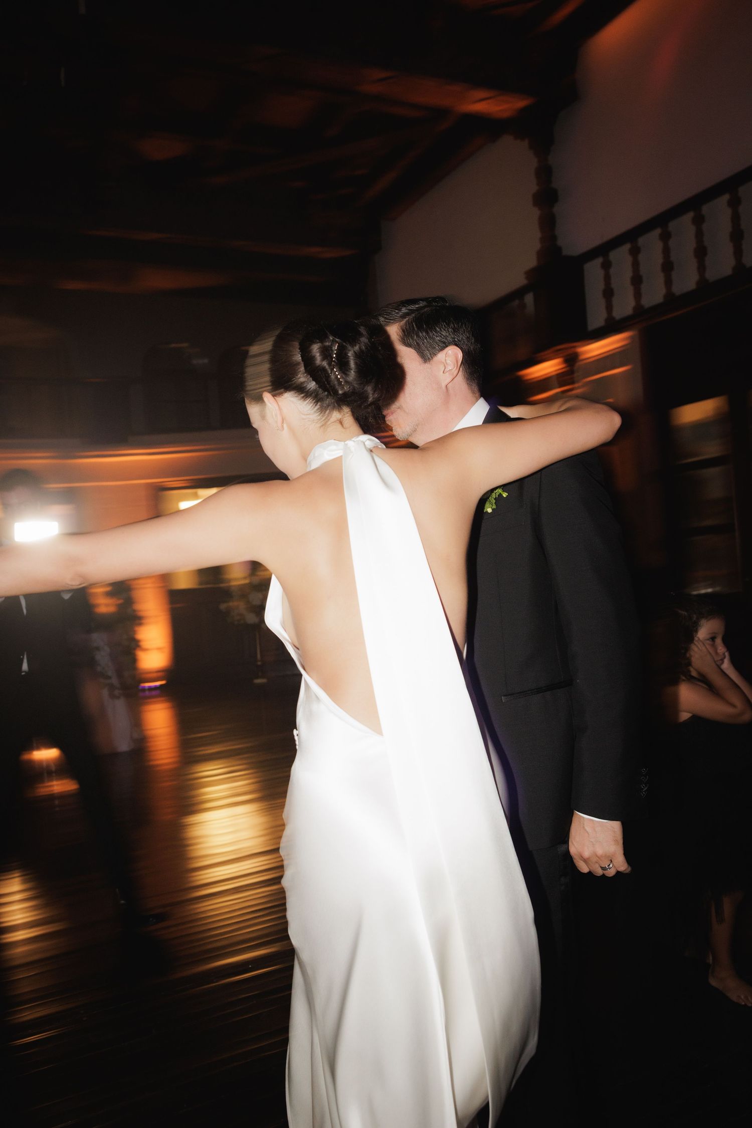 Couple dancing in dimly lit reception venue with romantic ambient lighting.