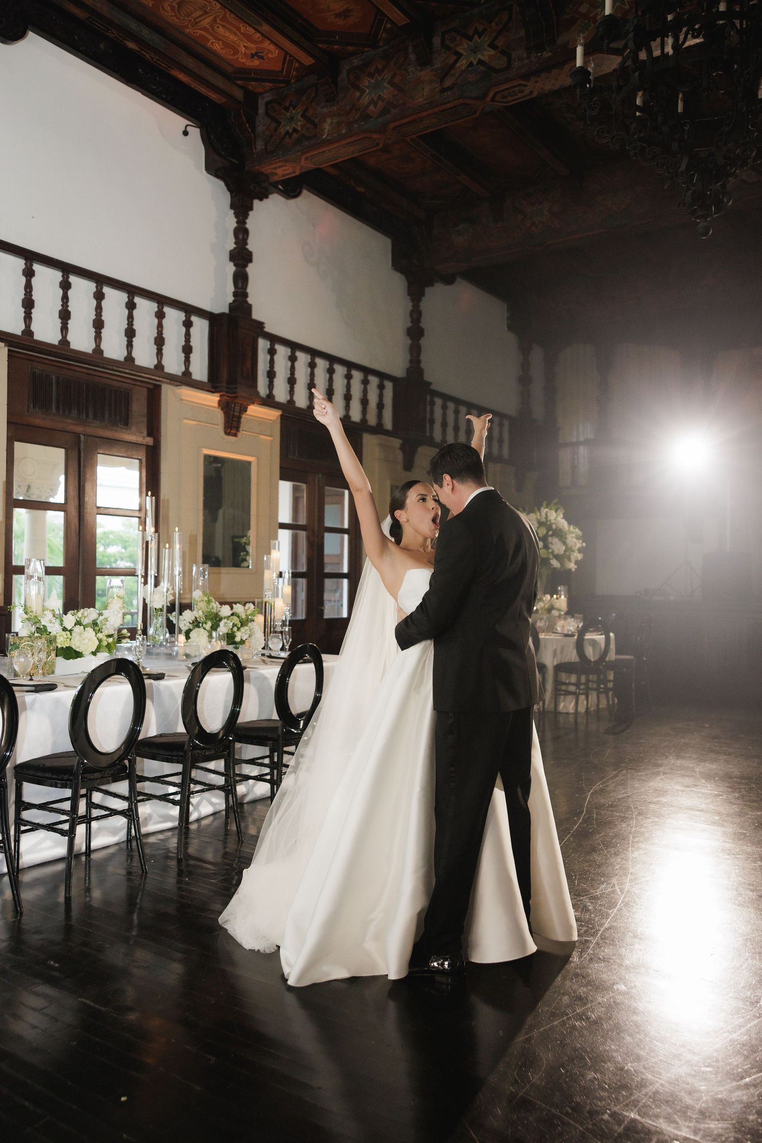 Romantic dance poses in an elegant ballroom with wooden beams and dramatic lighting.