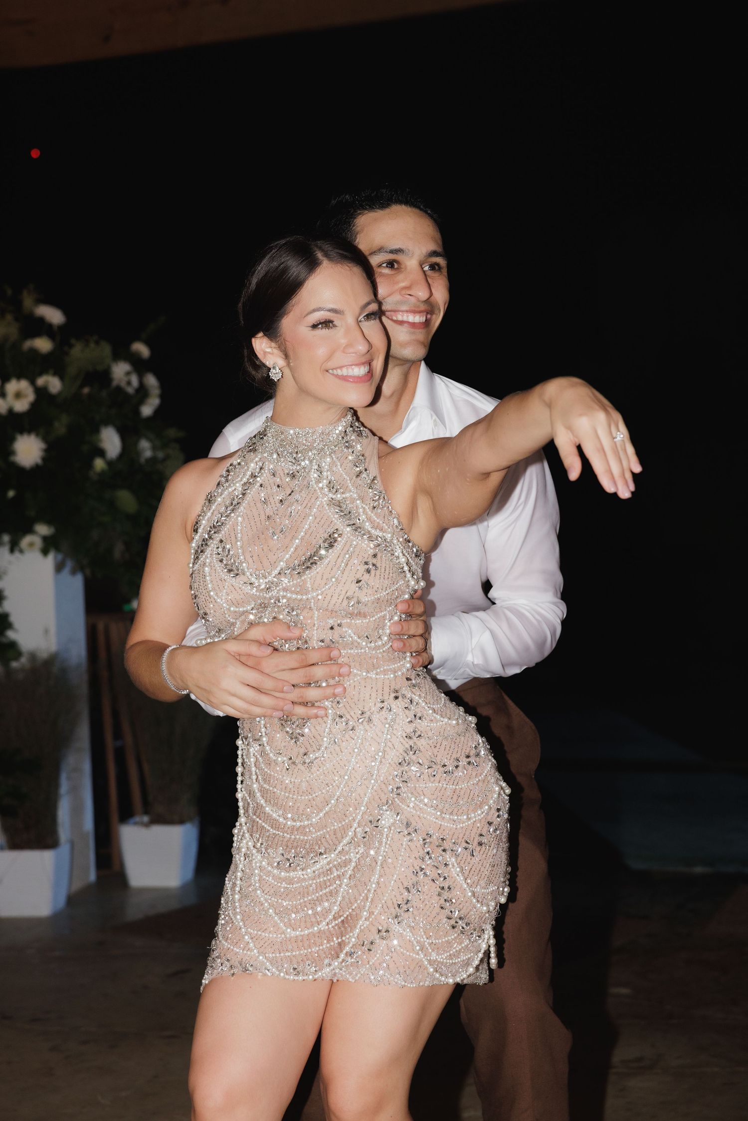 Couple dancing together at a party with the woman wearing a sparkly beaded dress.
