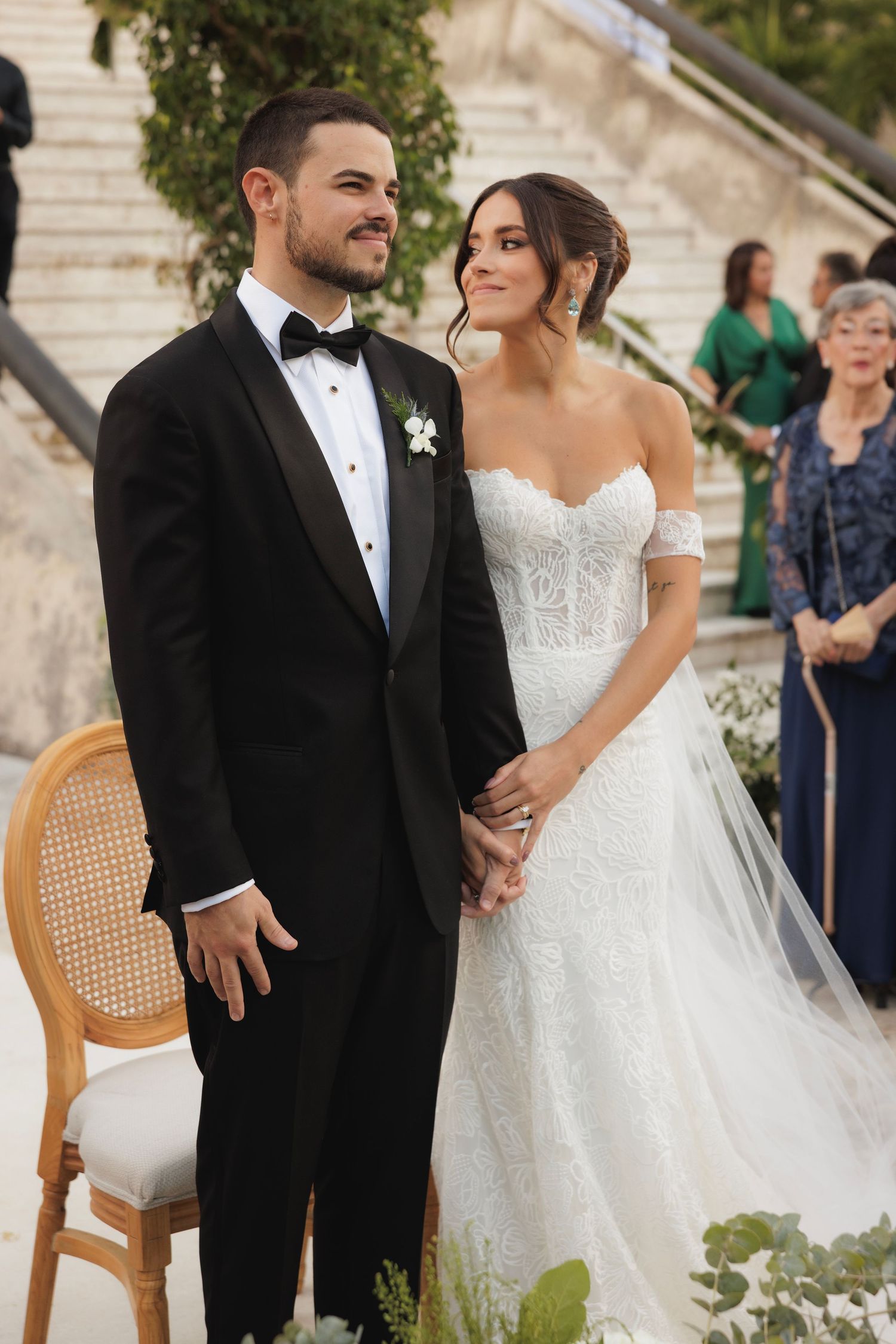 Wedding couple poses for portraits in formal attire against architectural backdrop.