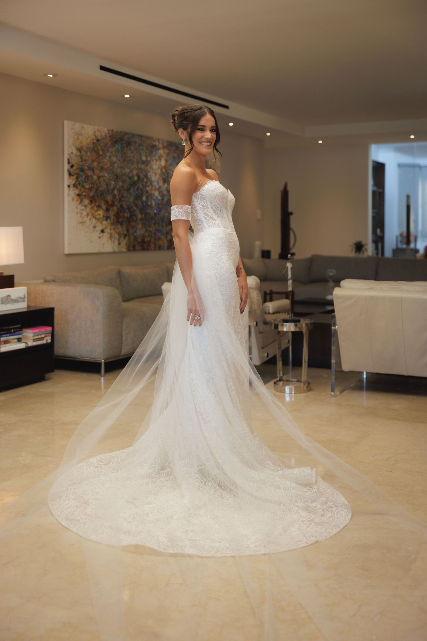 A stunning white wedding gown with a long flowing train displayed in an elegant showroom setting.