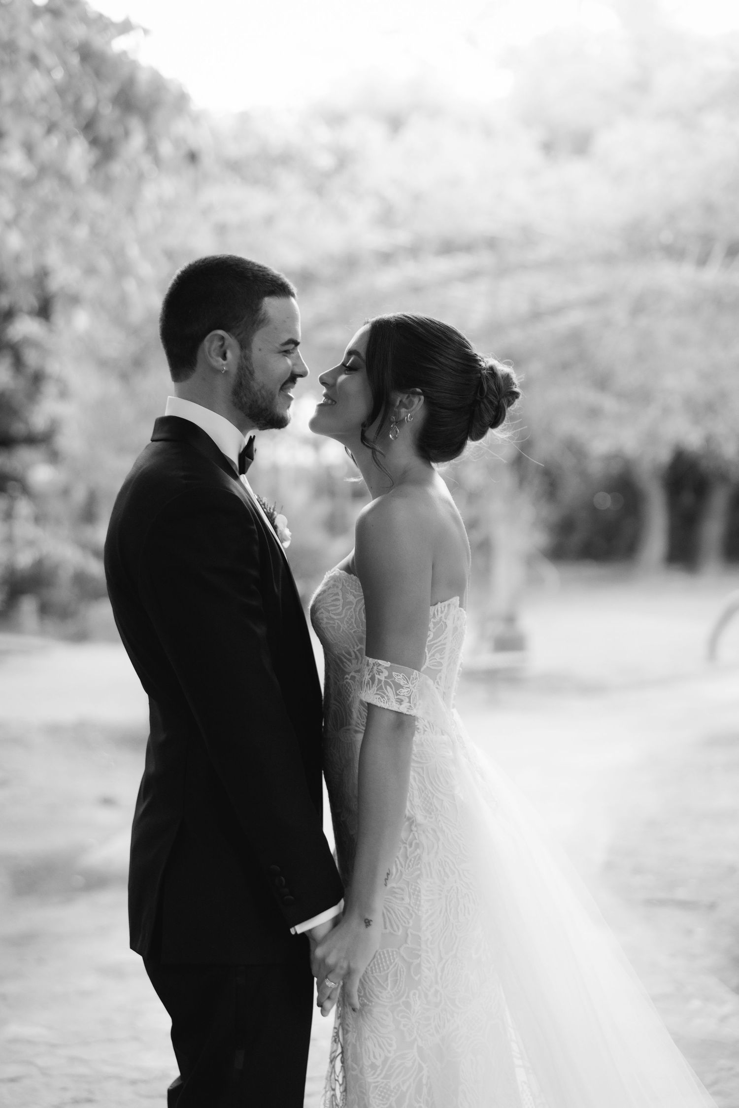 Intimate black and white wedding portrait of a couple about to kiss in an outdoor setting.