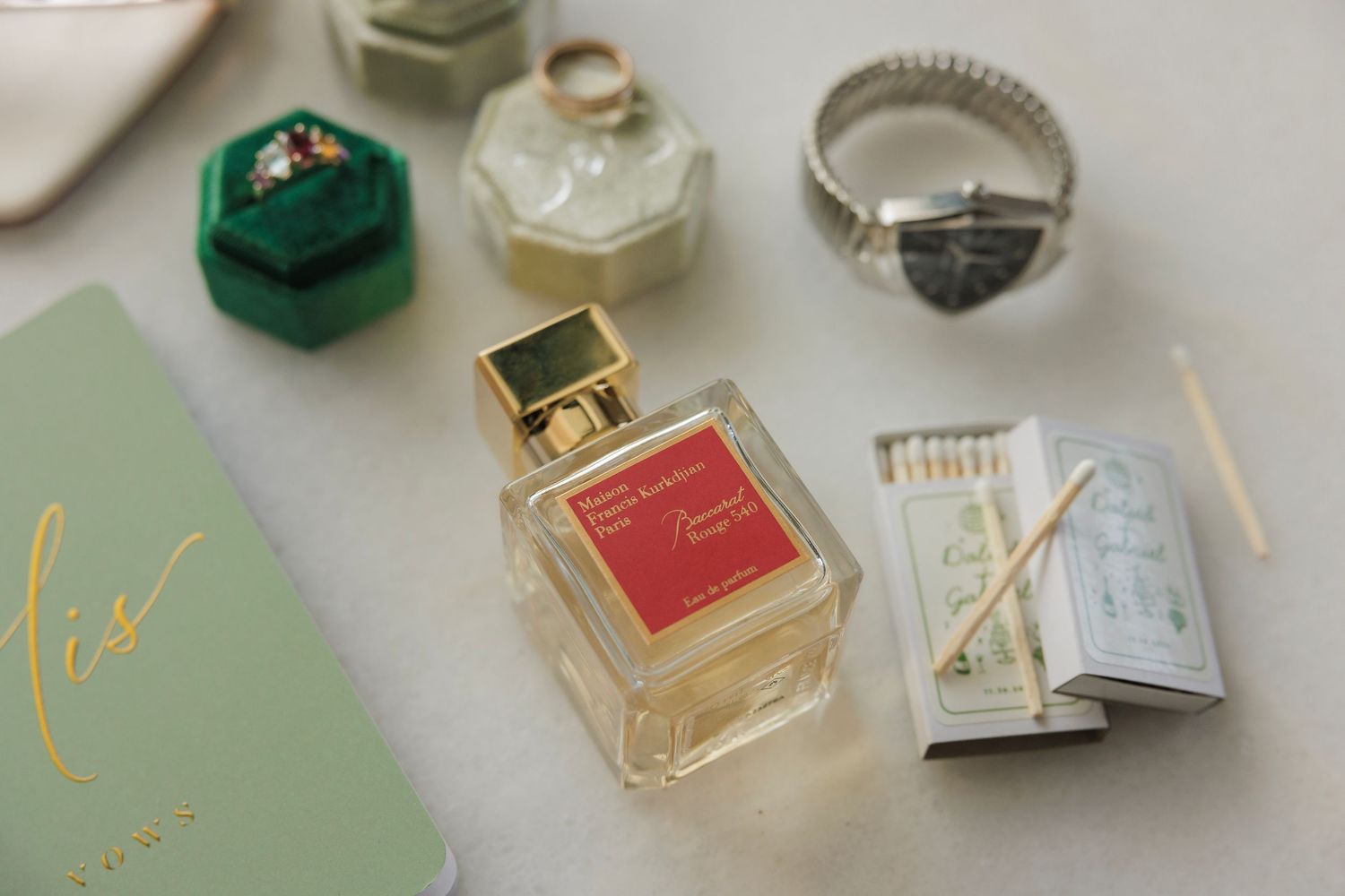 Perfume bottles, jewelry boxes and luxurious accessories arranged in an elegant flat lay composition against a white background.