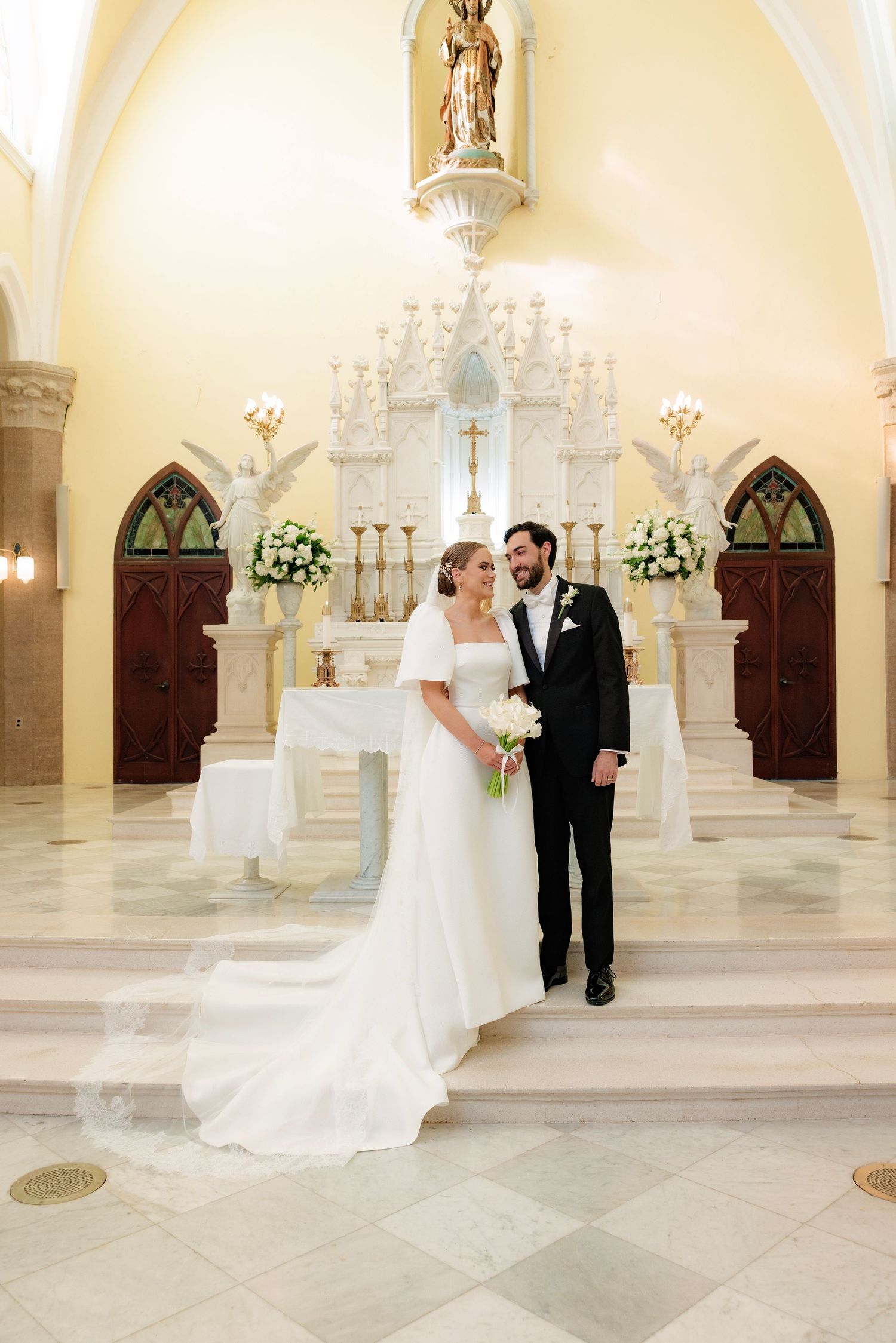 Elegant church altar with white floral arrangements and two decorative wooden doors on either side.