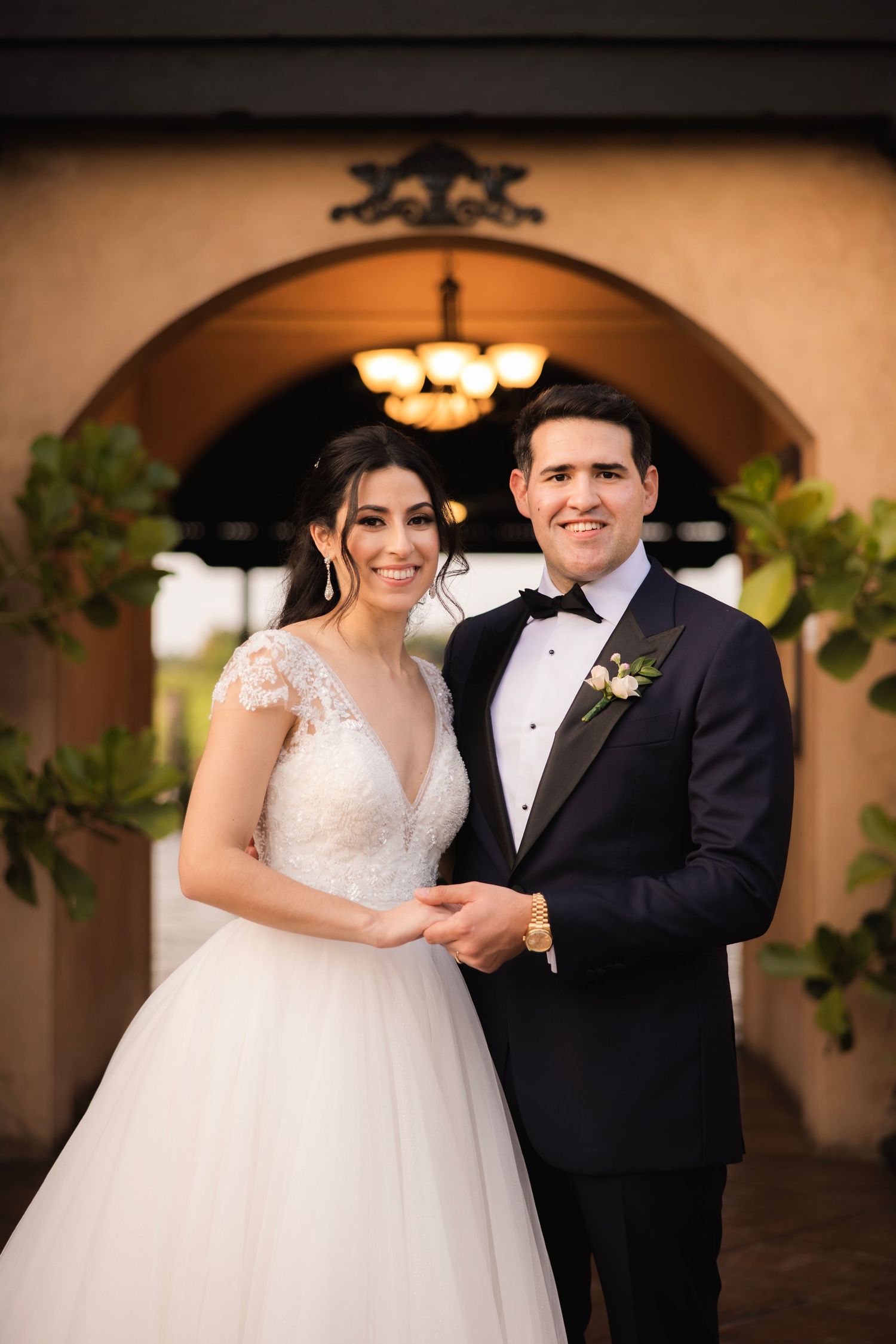 Wedding portraits under Spanish-style arches showcase elegant bride in ballgown and groom in classic tuxedo.