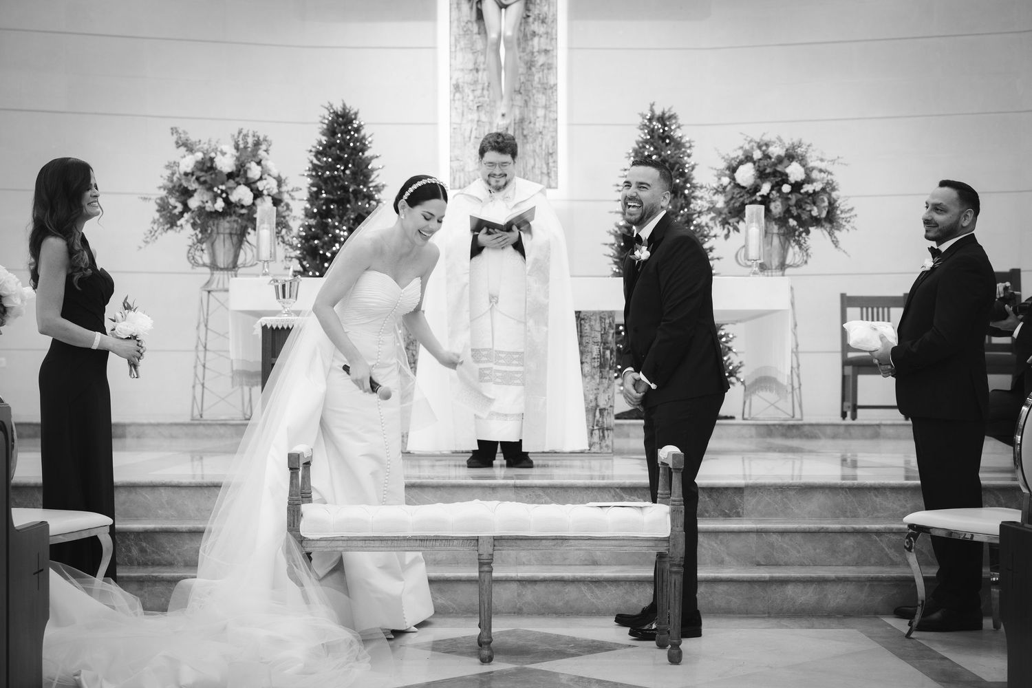 A black and white photograph of a wedding ceremony taking place at the altar in a church with holiday decor.