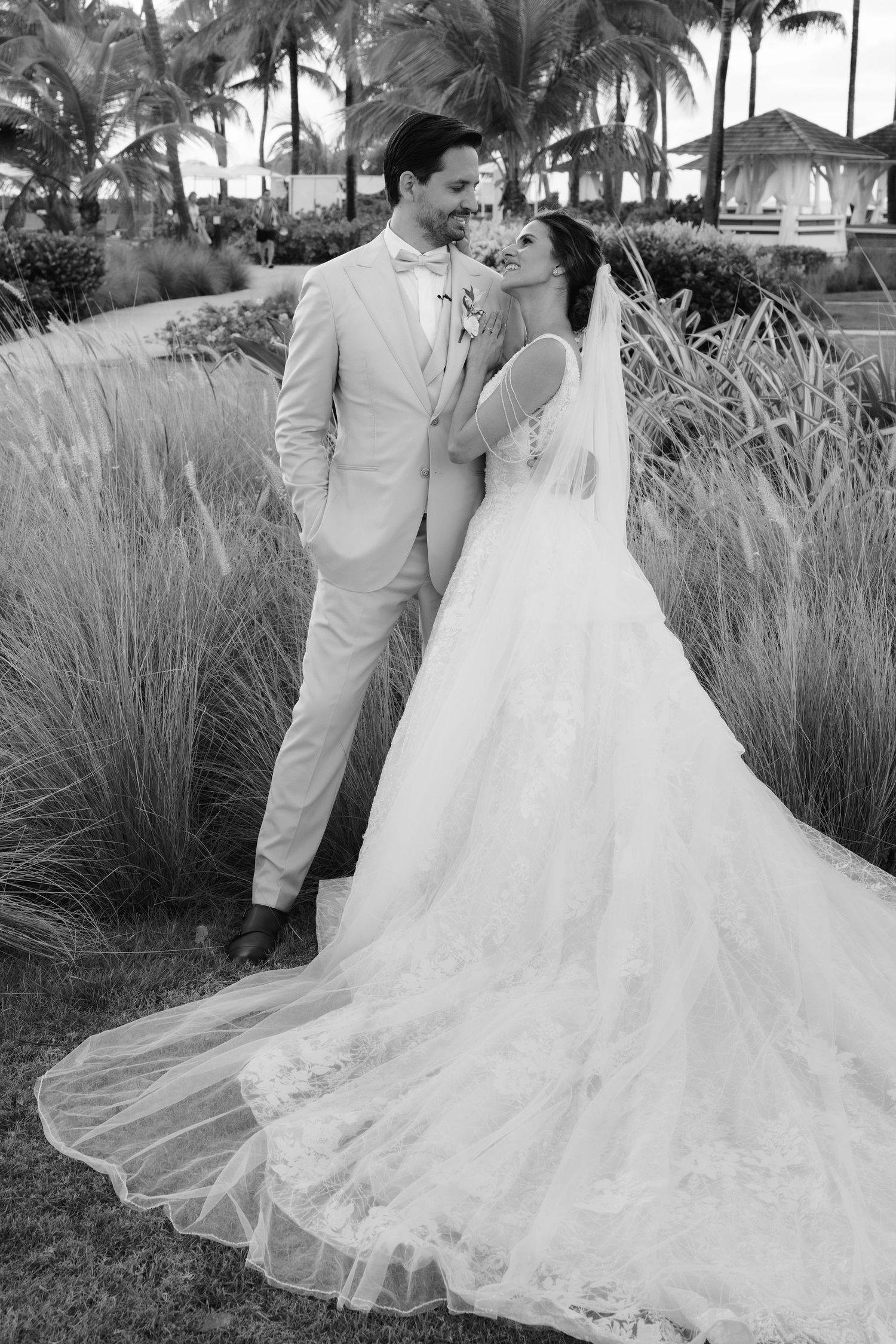 A romantic wedding photoshoot in a tropical garden with palm trees and ornamental grasses.