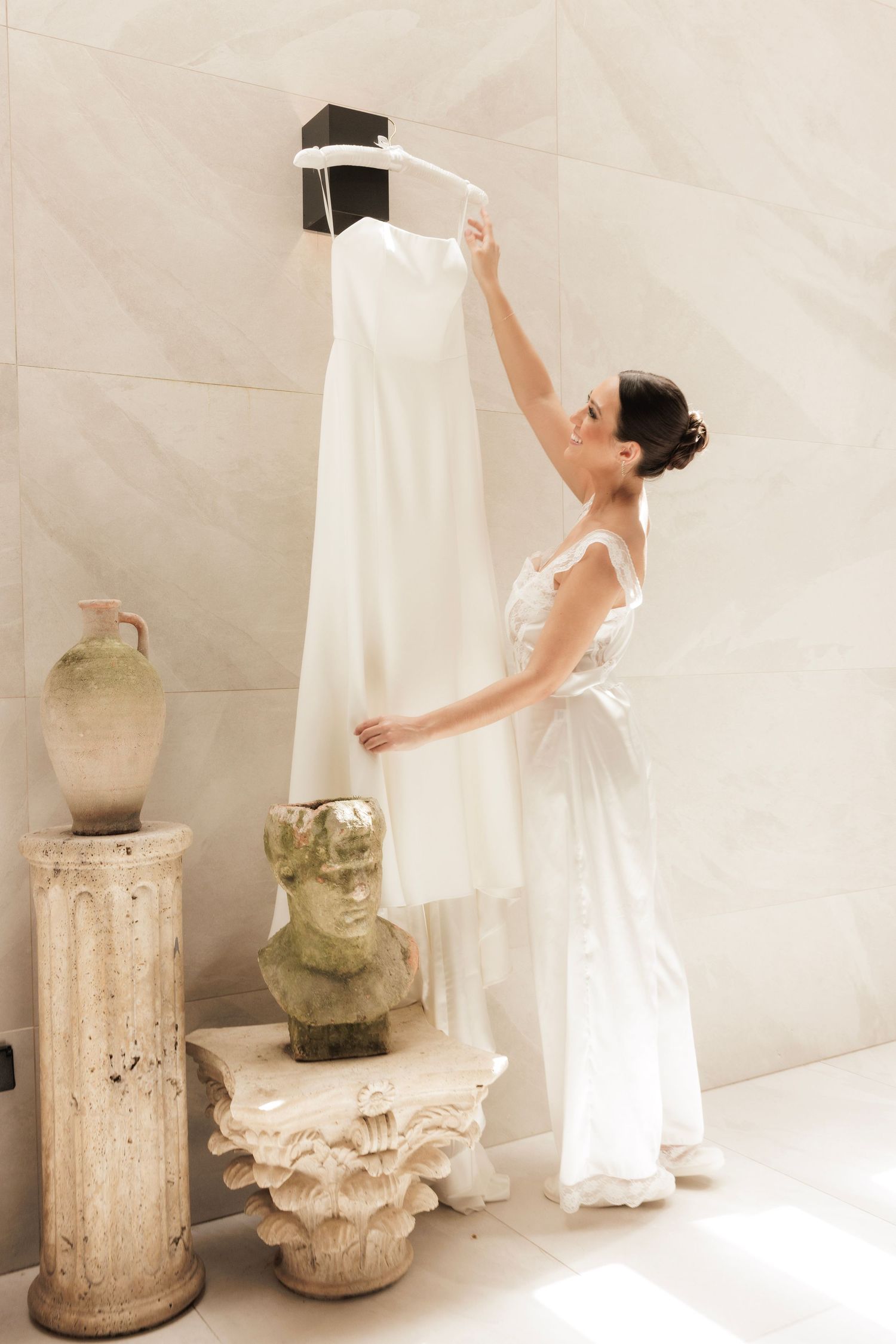 White dress flowing against a light background with vintage glass jars on rustic pedestals.