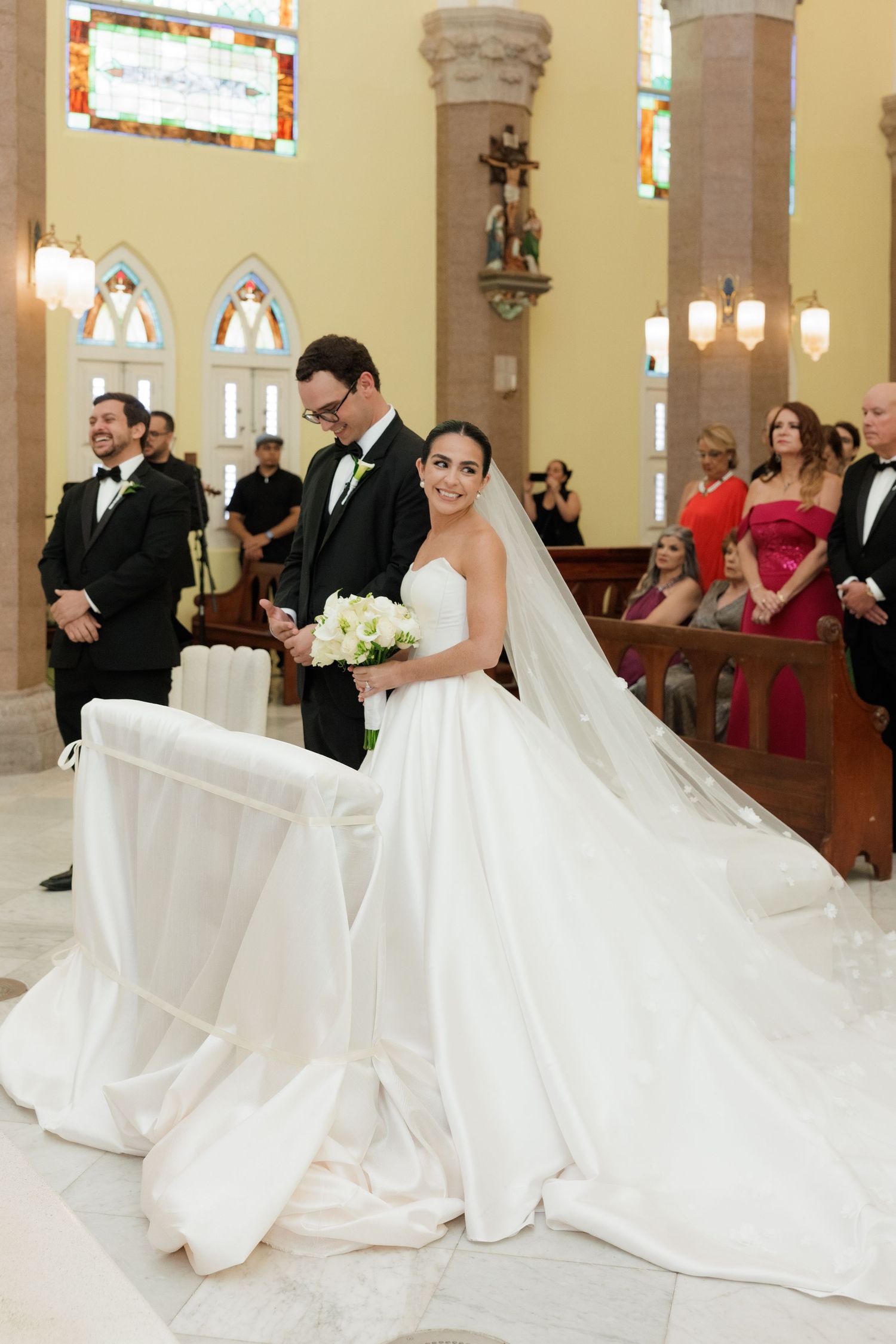 Elegant church wedding ceremony with bride in flowing white gown and guests in formal attire.