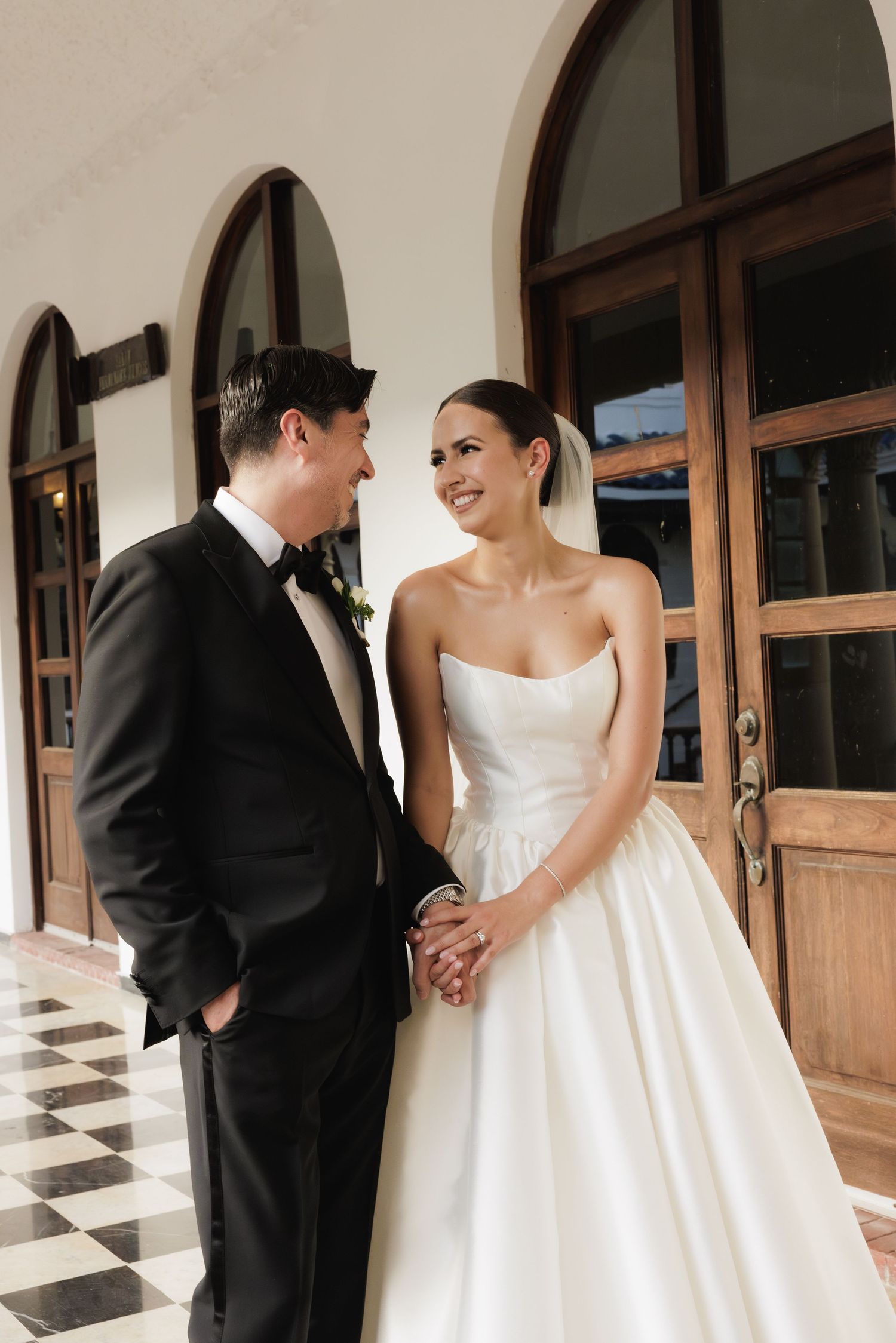 Intimate wedding photos captured in sequence along an elegant colonnade with black and white marble floors.