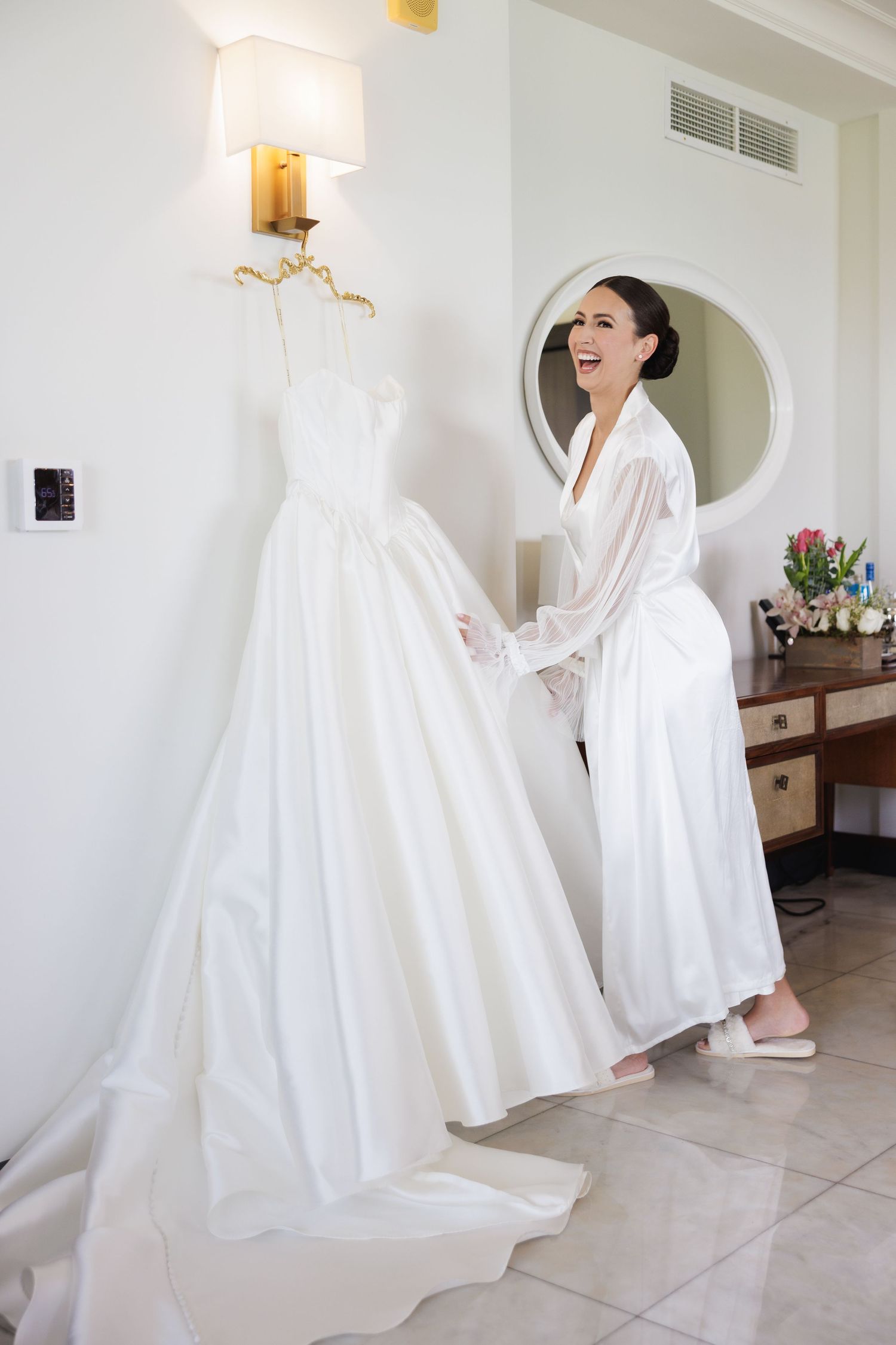 A wedding dress preparation moment showing elegant white ballgown in natural light.