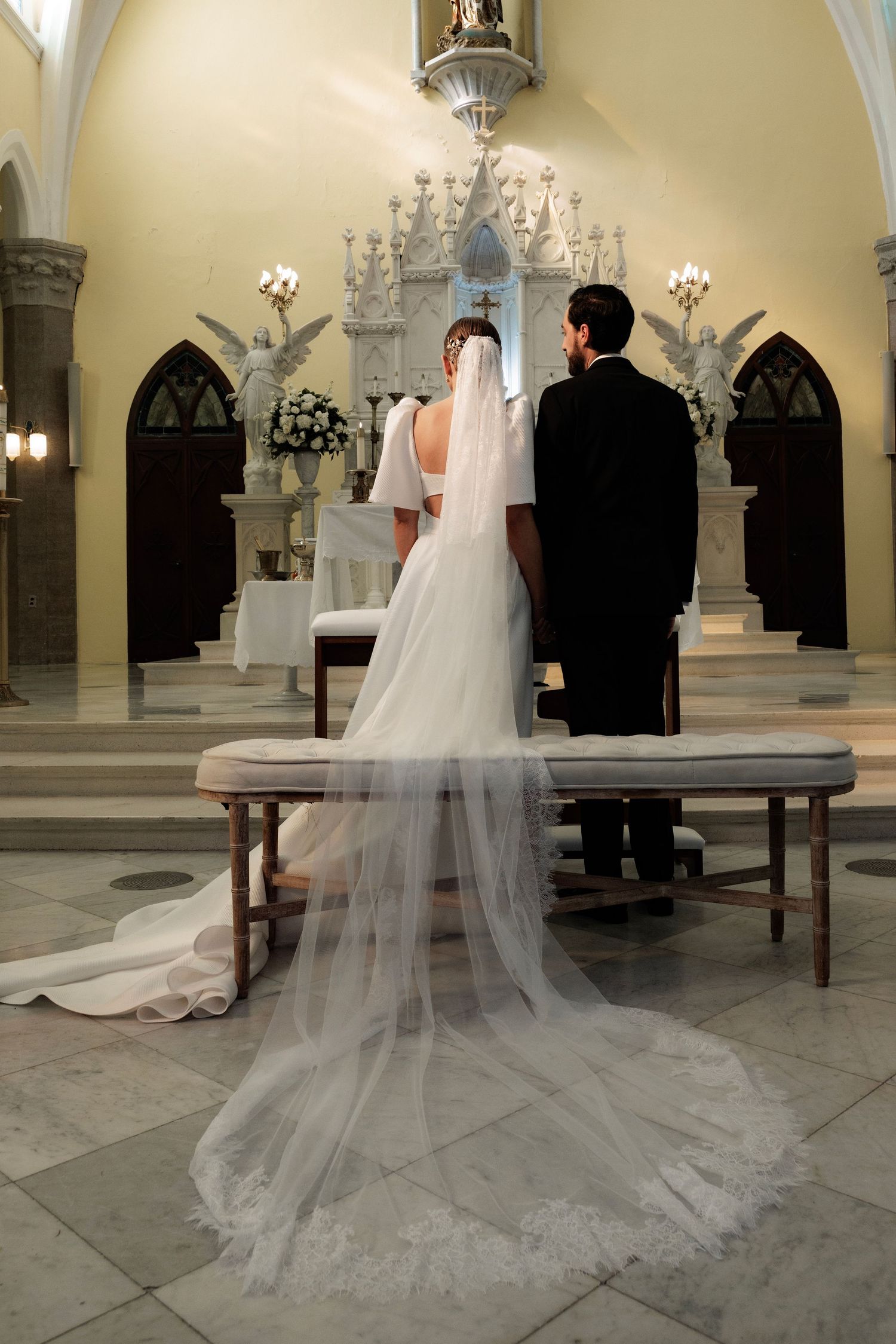 A wedding ceremony in a cathedral with a dramatic long veil trailing across the marble floor.