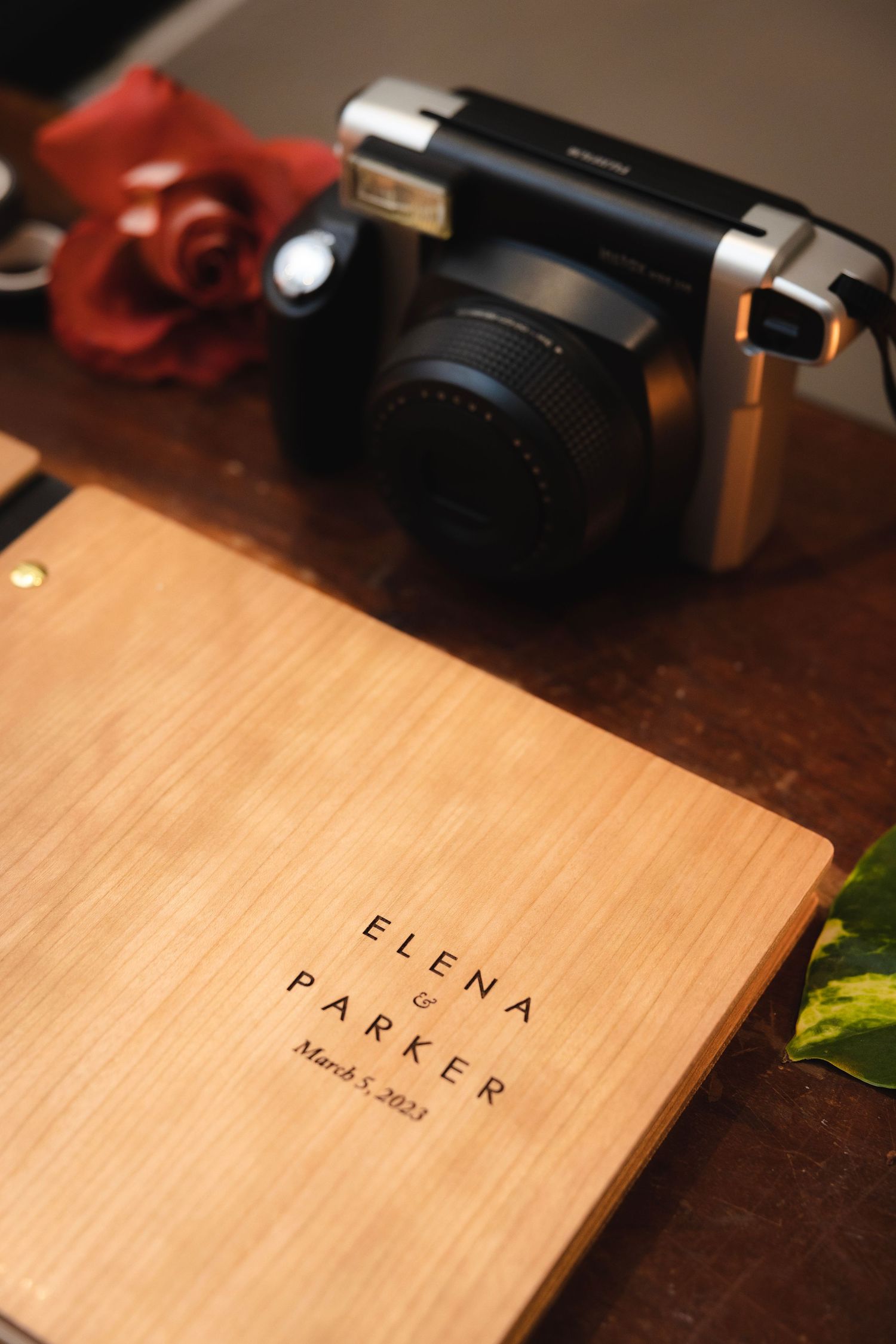 Wooden name place cards with elegant text displayed on a dark surface with camera equipment in the background.
