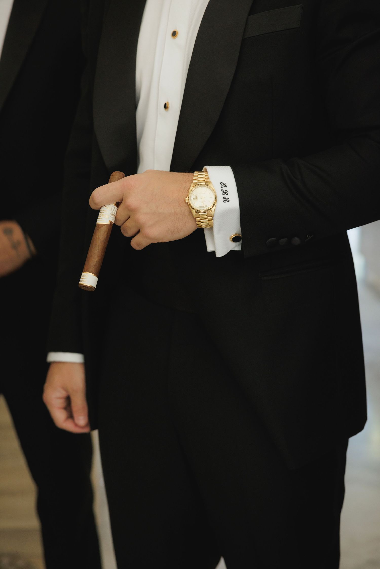 Detail shots of formal black tuxedo with gold watch and cufflinks.