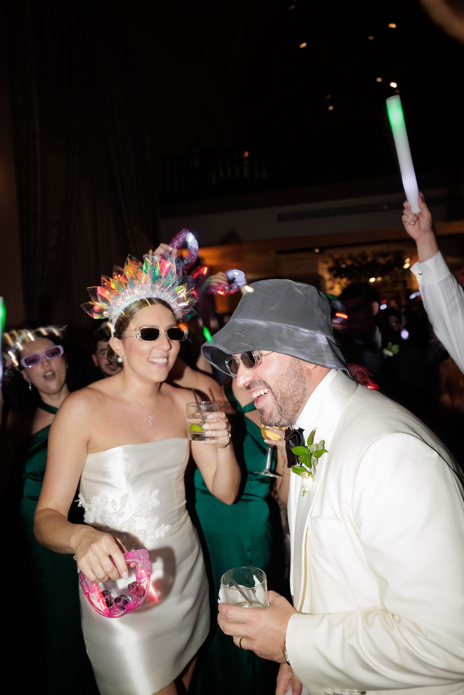 Party scene with glowsticks and colorful accessories as people dance and celebrate.